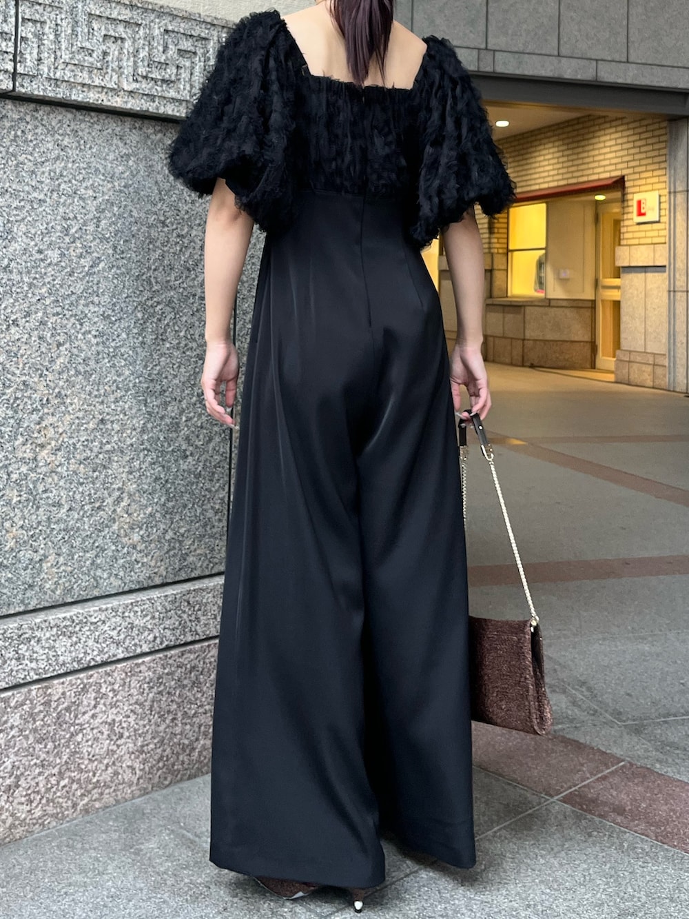 その他のパンプス、ブラック系のパンツドレス、その他のクラッチバッグを着用したレディースの冬コーディネートの4枚目の写真