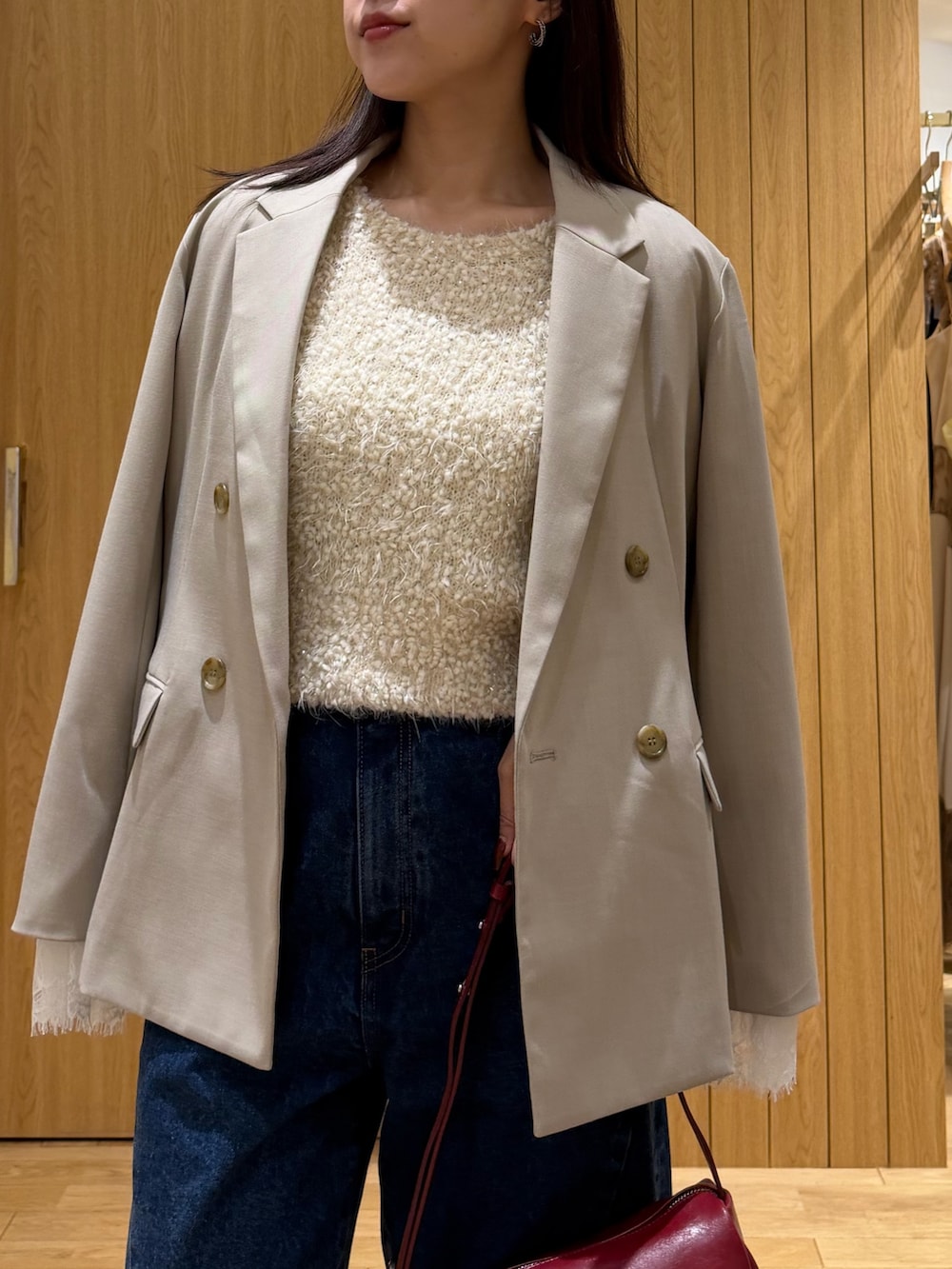 ブルー系のデニムパンツ、レッド系のハンドバッグ、ブラック系のブーツを着用したレディースの秋コーディネートの7枚目の写真