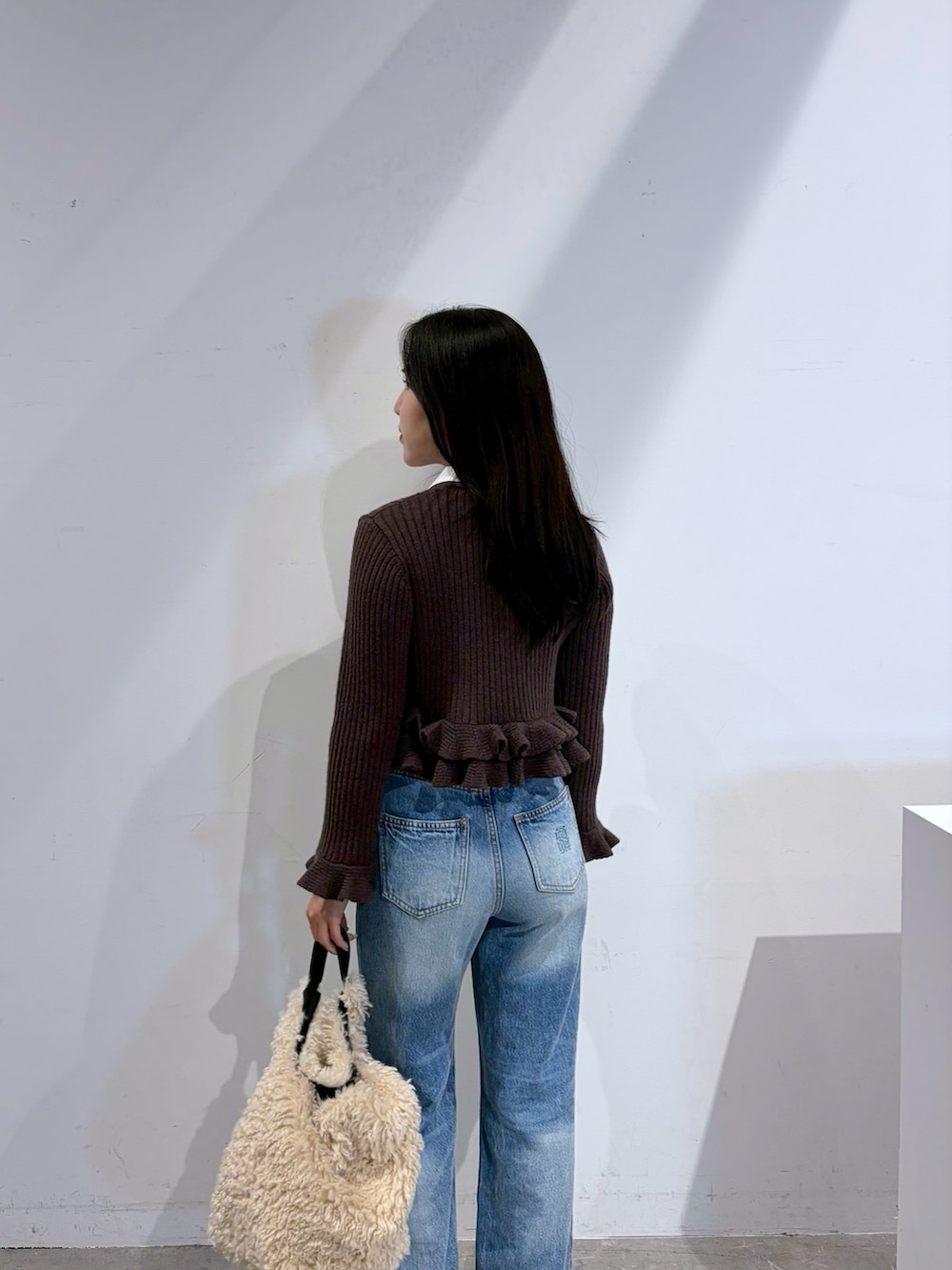 ブラウン系のニット/セーター、ブルー系のデニムパンツ、ブラック系のブーツを着用したレディースの夏コーディネートの6枚目の写真