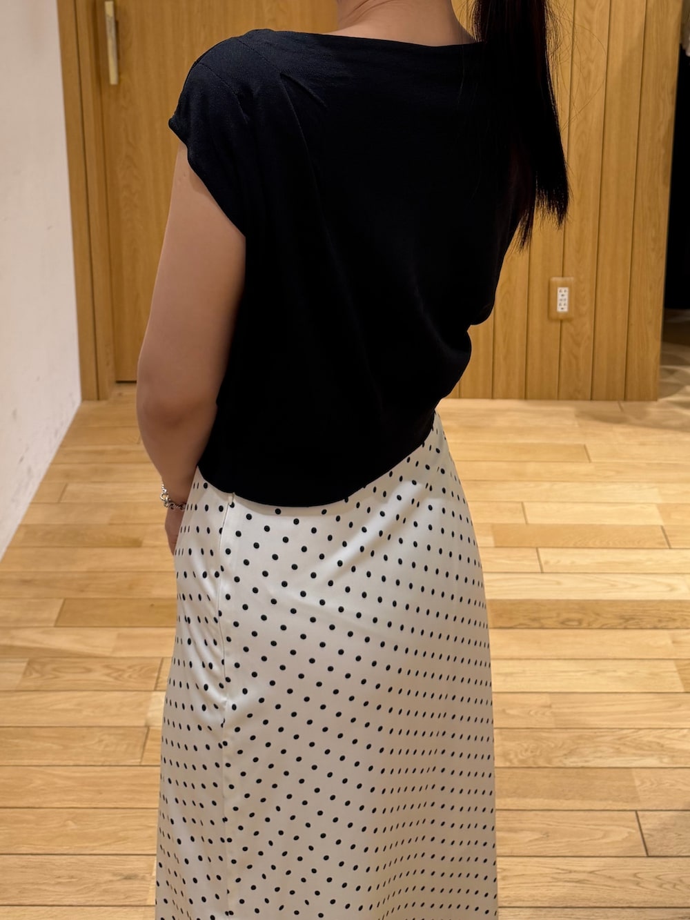ブラック系のパンプス、ブラック系のニット/セーター、ホワイト系のスカートを着用したレディースの夏コーディネートの5枚目の写真