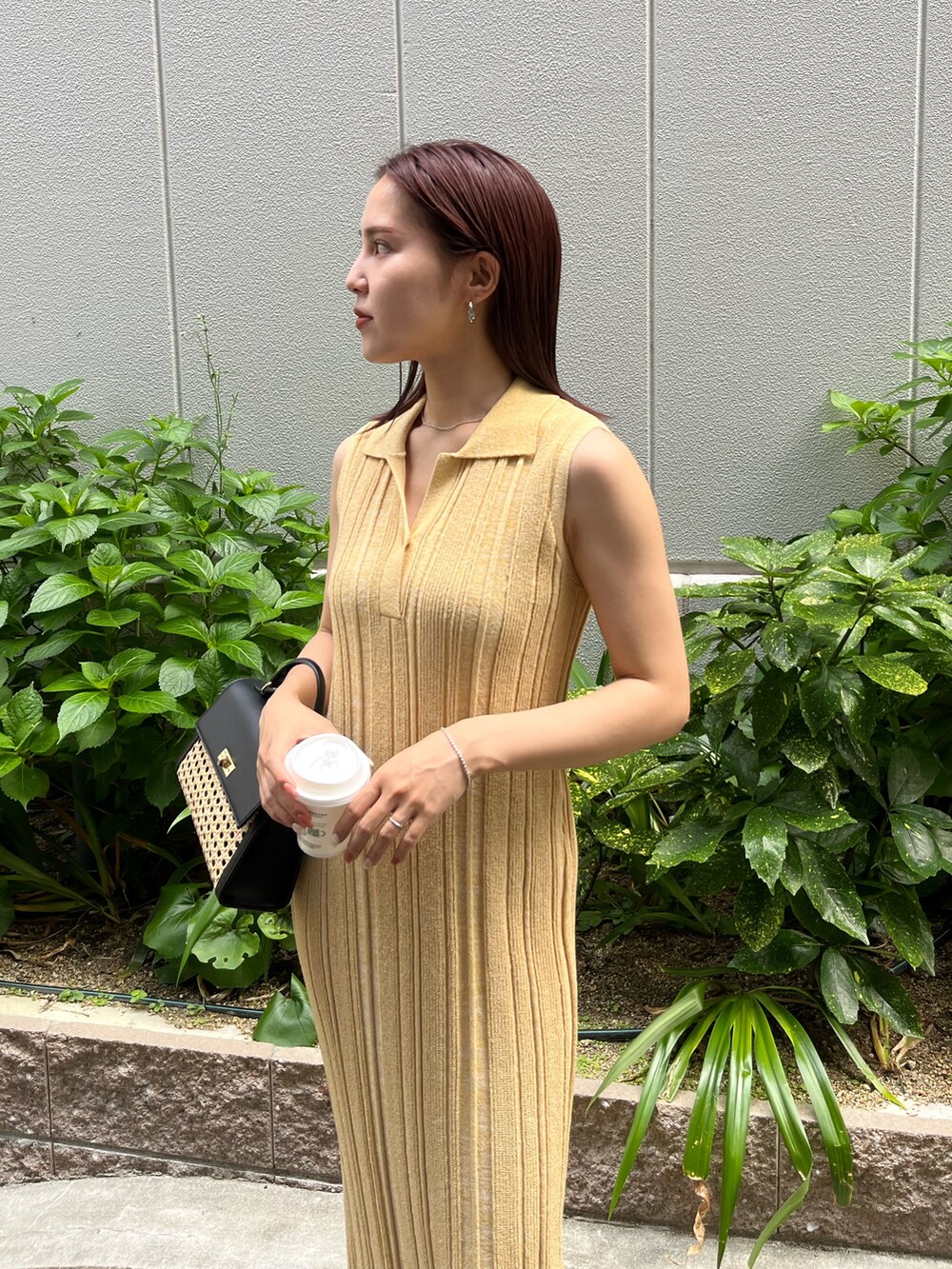 イエロー系のワンピース、ブラック系のハンドバッグ、ブラック系のサンダルを着用したレディースの夏コーディネートの5枚目の写真