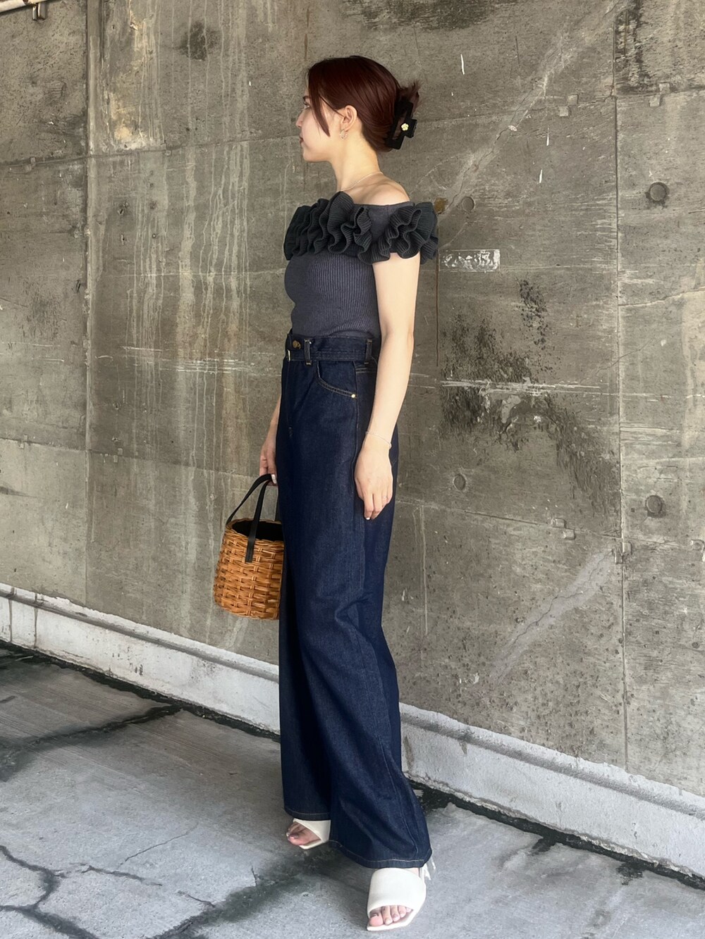 グレー系のニット/セーター、ブラウン系のハンドバッグ、ブルー系のデニムパンツを着用したレディースの夏コーディネートの2枚目の写真