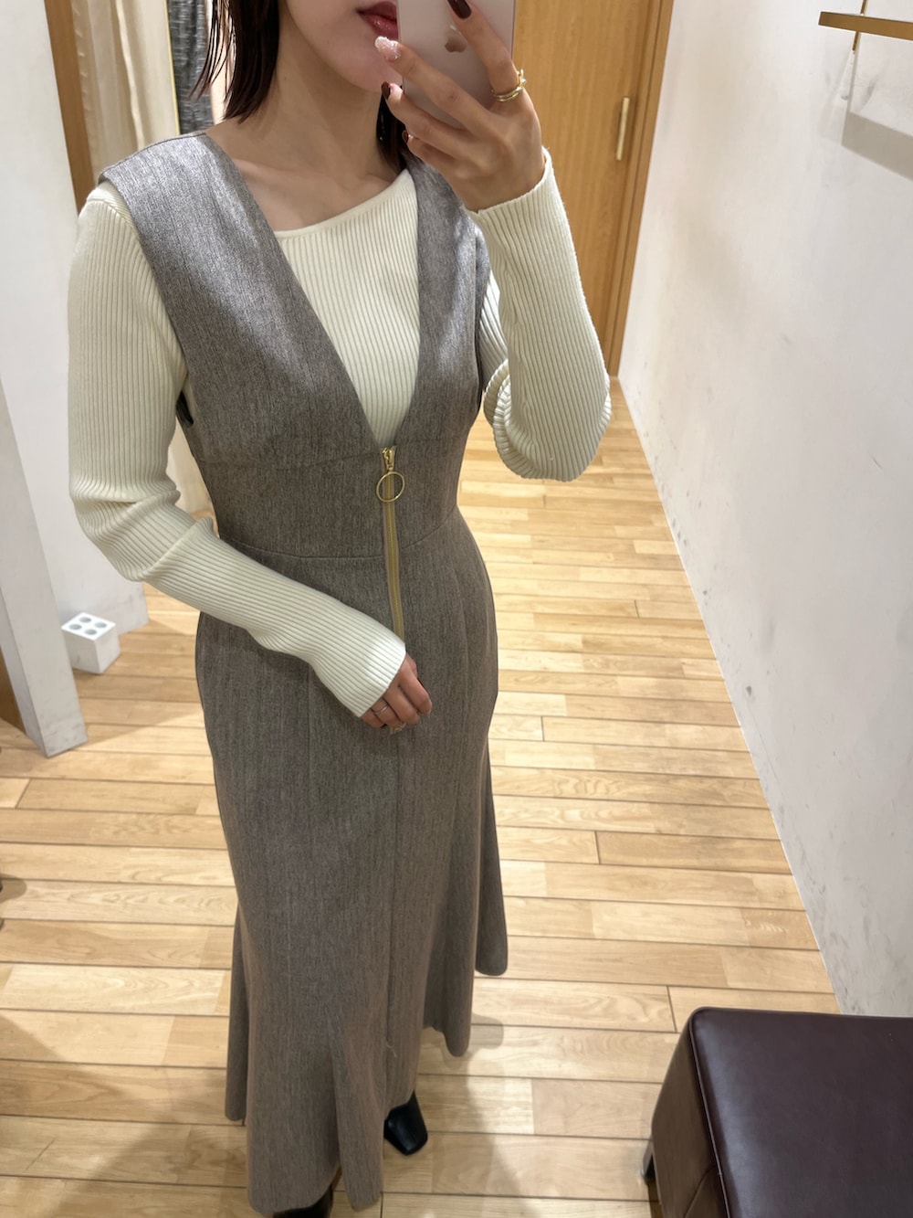 ブラック系のブーツ、ホワイト系のニット/セーター、ベージュ系のジャンパースカートを着用したレディースの冬コーディネートの5枚目の写真