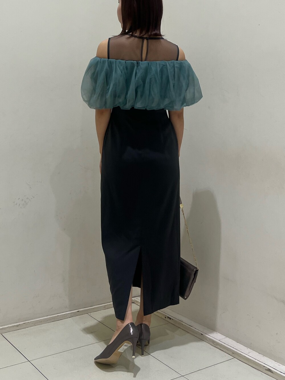 シルバー系のクラッチバッグ、シルバー系のパンプス、グレー系のドレスを着用したレディースの冬コーディネートの3枚目の写真