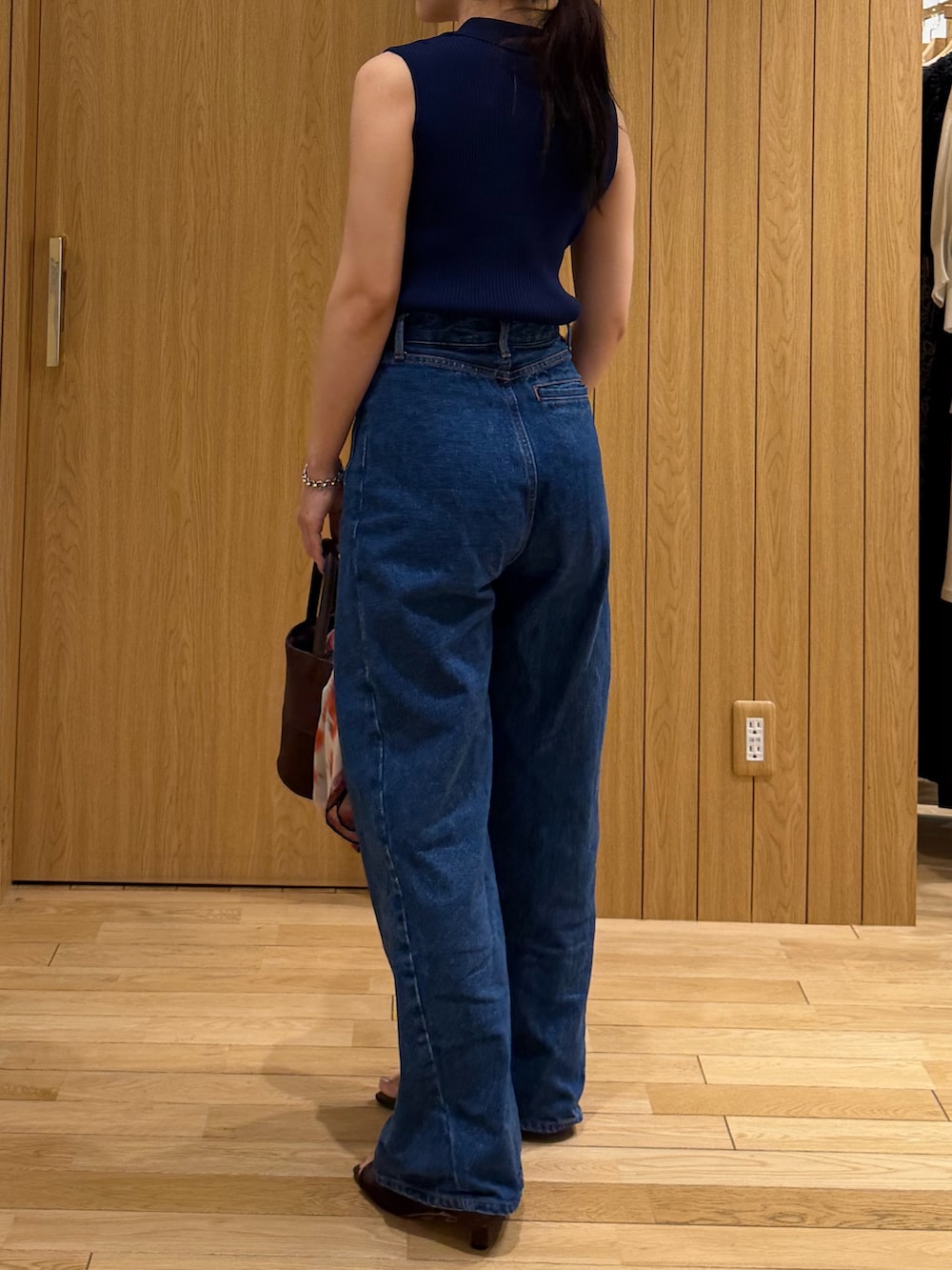 ブルー系のデニムパンツ、ブルー系のニット/セーター、ブラウン系のサンダルを着用したレディースの夏コーディネートの3枚目の写真