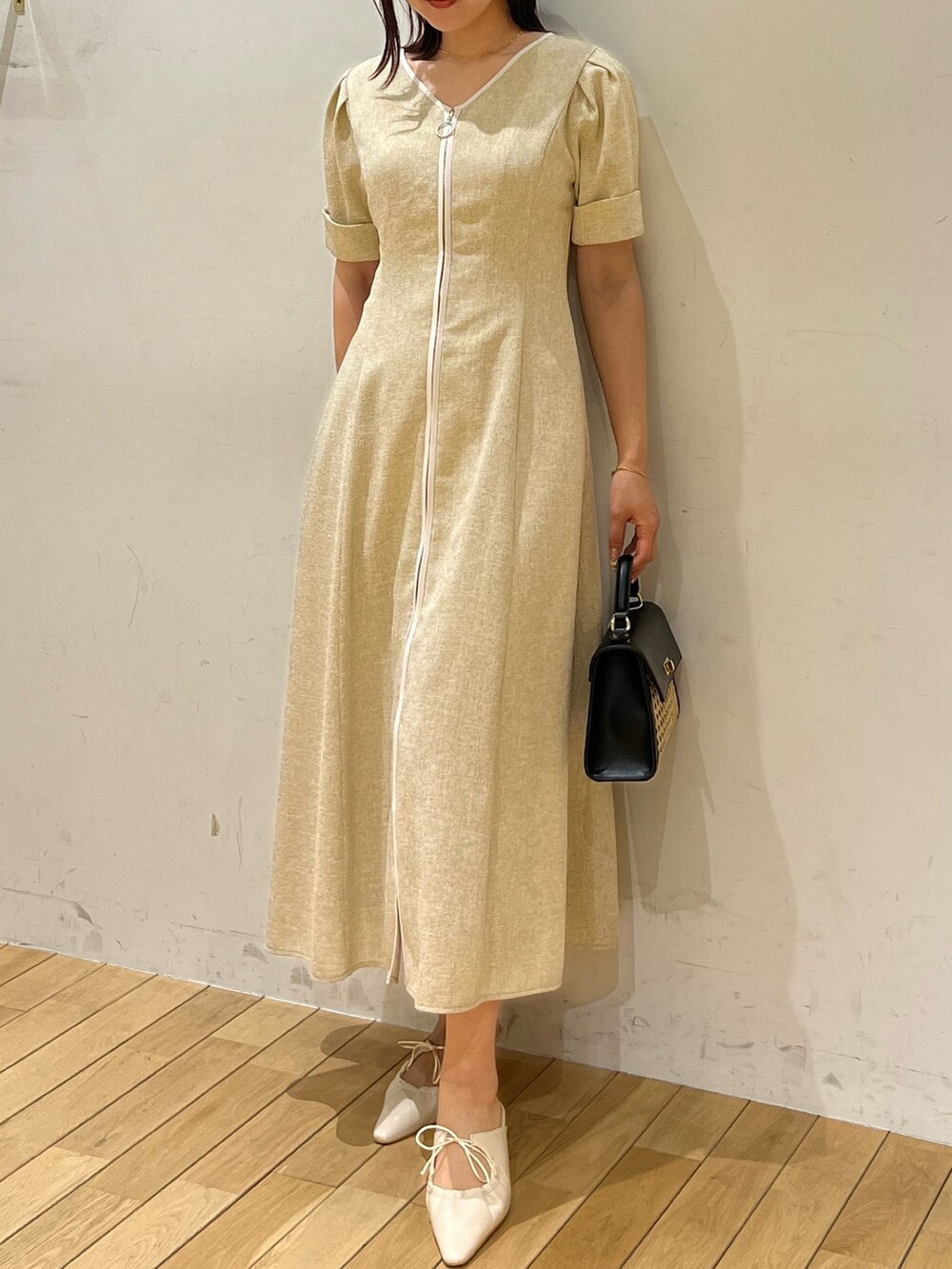 ベージュ系のワンピース、ホワイト系のサンダル、ブラック系のハンドバッグを着用したレディースの春コーディネートの4枚目の写真