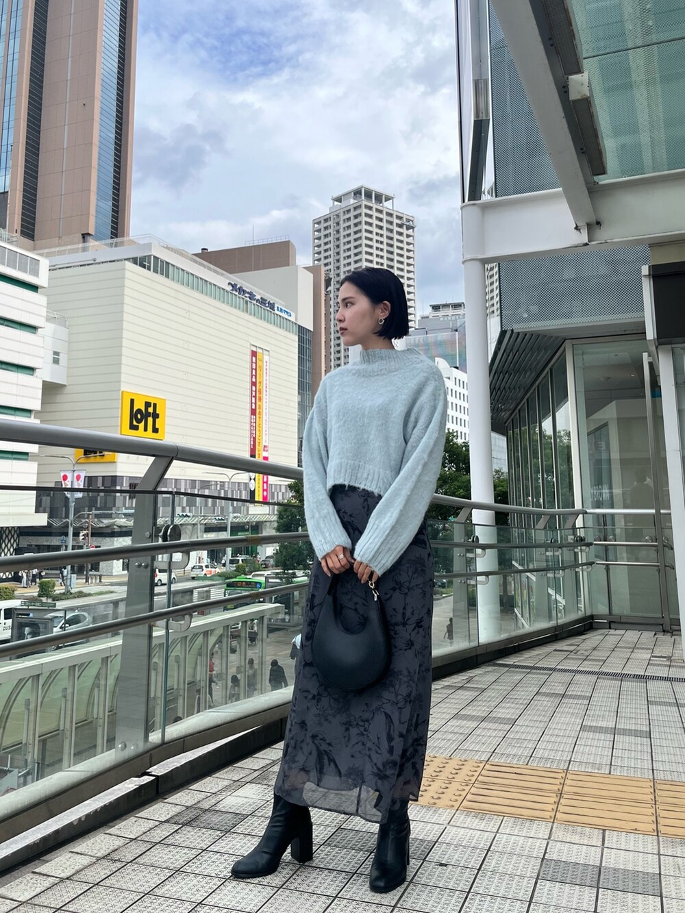 ホワイト系のムートンコート、グリーン系のニット/セーター、グレー系のスカートを着用したレディースの秋コーディネートの7枚目の写真