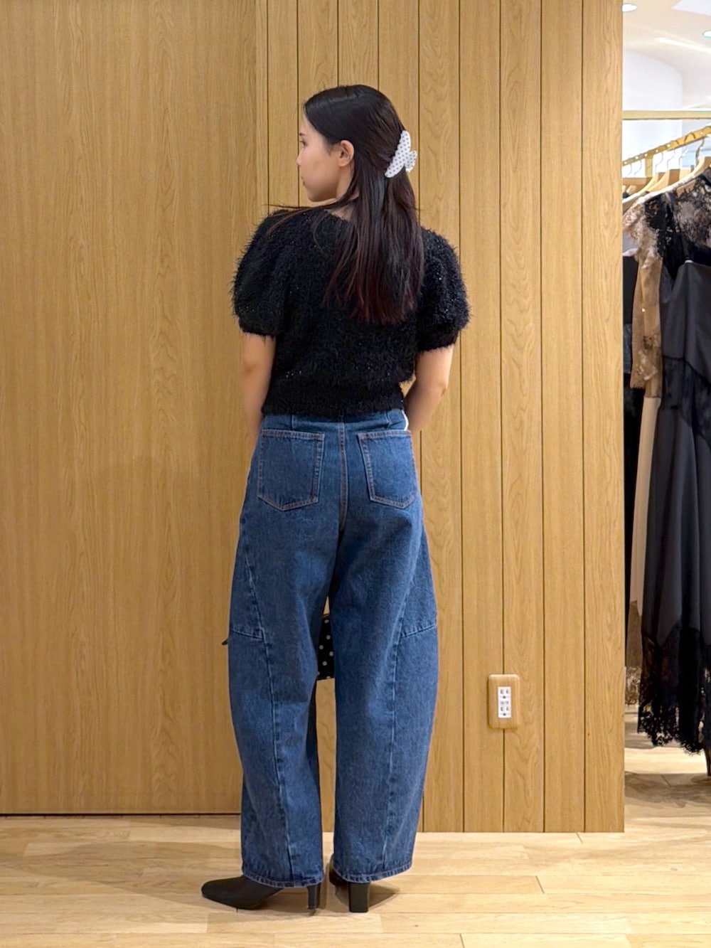 ブルー系のデニムパンツ、ブラック系のニット/セーター、ブラック系のハンドバッグを着用したレディースの秋コーディネートの3枚目の写真
