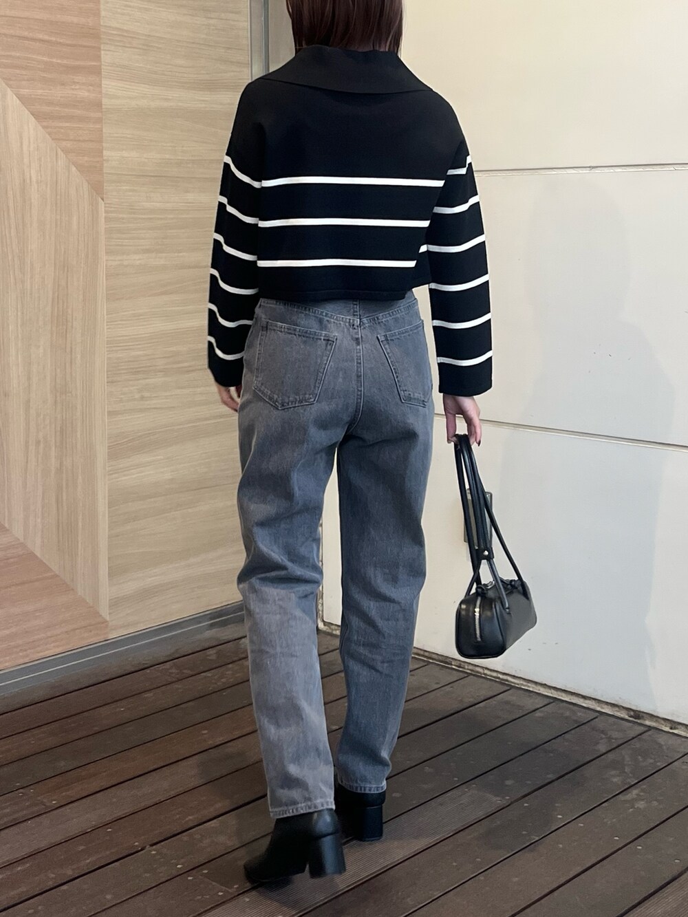 ブラック系のデニムパンツ、ブラック系のニット/セーター、ブラック系のショルダーバッグを着用したレディースの冬コーディネートの3枚目の写真