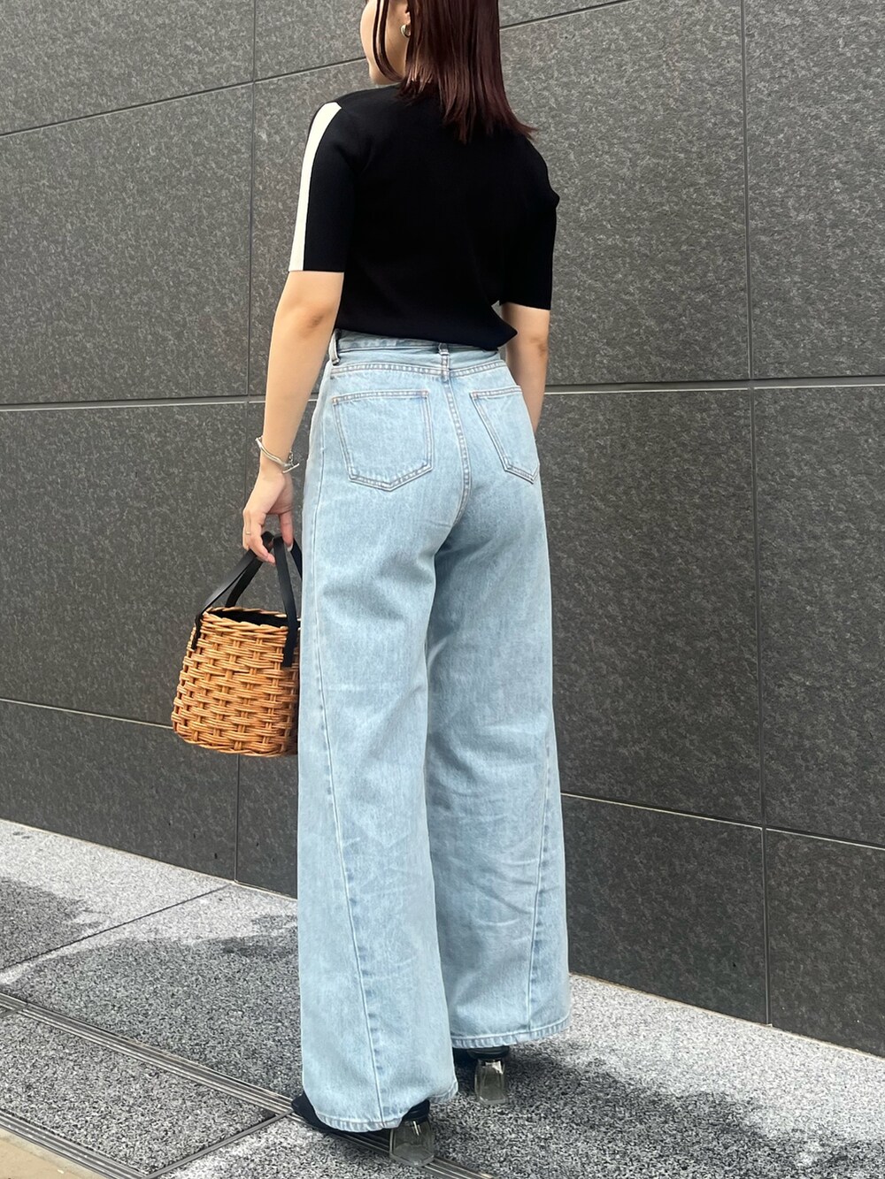 ブラック系のニット/セーター、ブルー系のデニムパンツ、ブラウン系のハンドバッグを着用したレディースの夏コーディネートの3枚目の写真