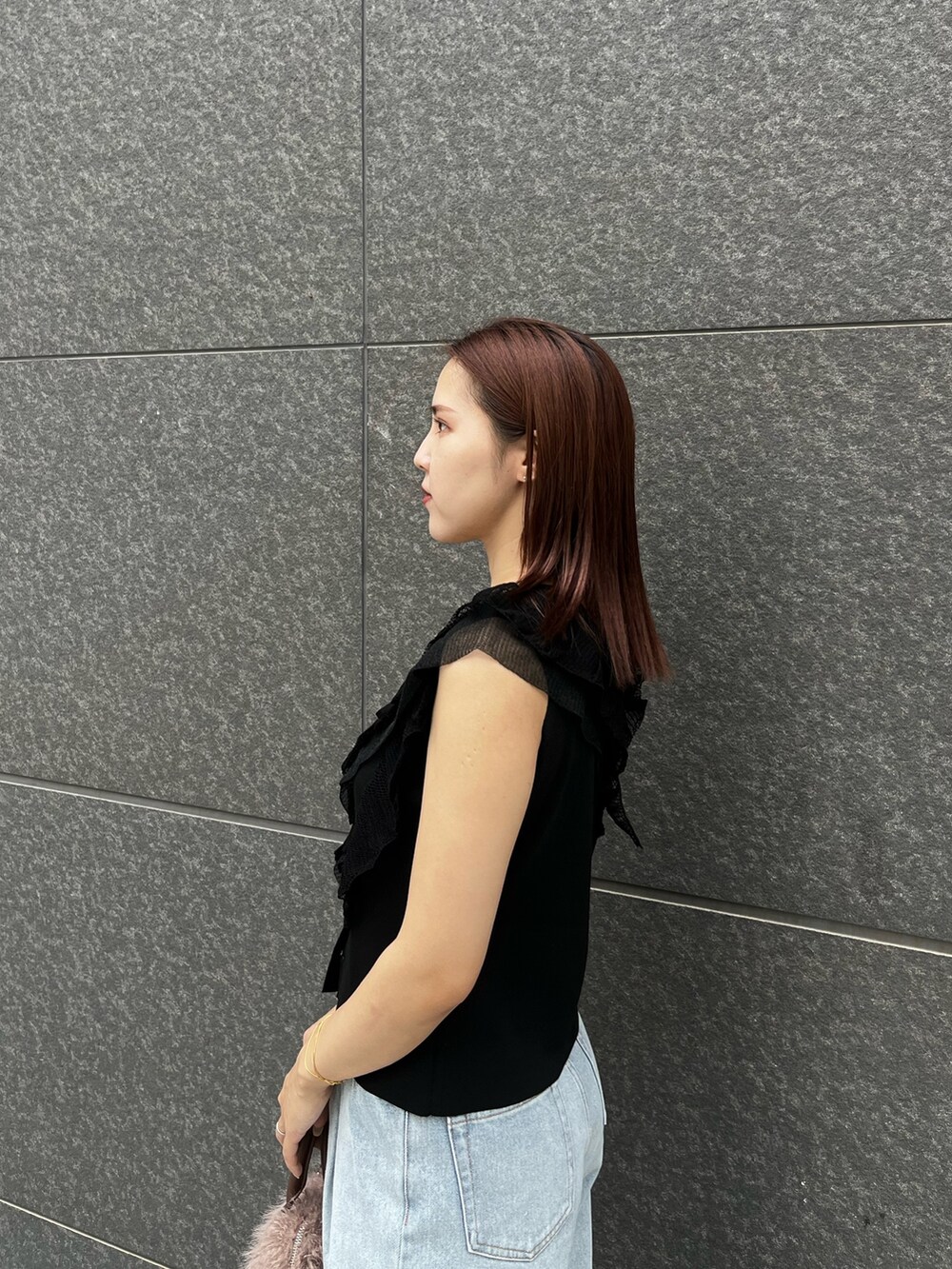ブラック系のニット/セーター、ブルー系のデニムパンツ、ベージュ系のボストンバッグを着用したレディースの夏コーディネートの5枚目の写真