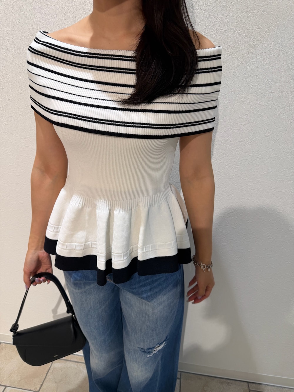 ブルー系のデニムパンツ、ブラック系のハンドバッグ、グリーン系のパンプスを着用したレディースの夏コーディネートの7枚目の写真