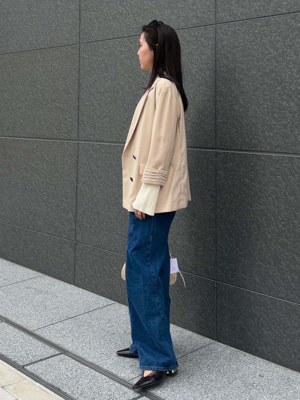 ベージュ系のテーラードジャケット、ホワイト系のニット/セーター、ブルー系のデニムパンツを着用したレディースの春コーディネートの2枚目の写真