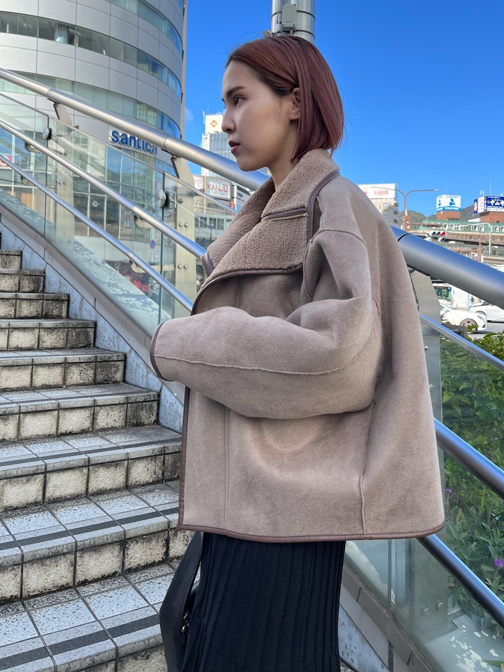 ブラック系のワンピース、ベージュ系のブーツ、ブラック系のハンドバッグを着用したレディースの秋コーディネートの4枚目の写真