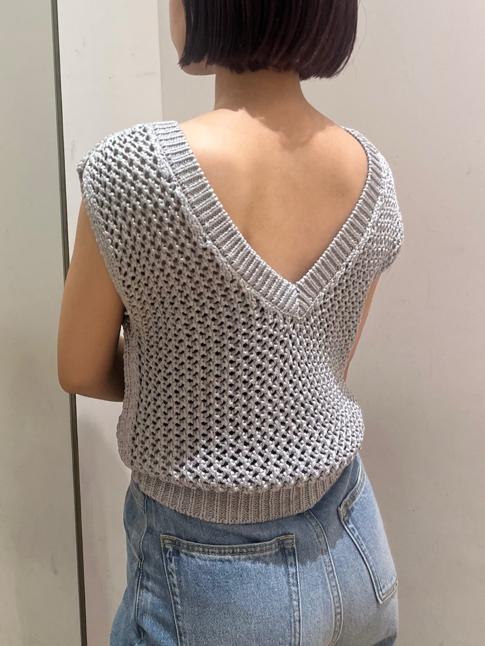 シルバー系のニット/セーター、ブルー系のデニムパンツ、ブラック系のハンドバッグを着用したレディースの夏コーディネートの4枚目の写真