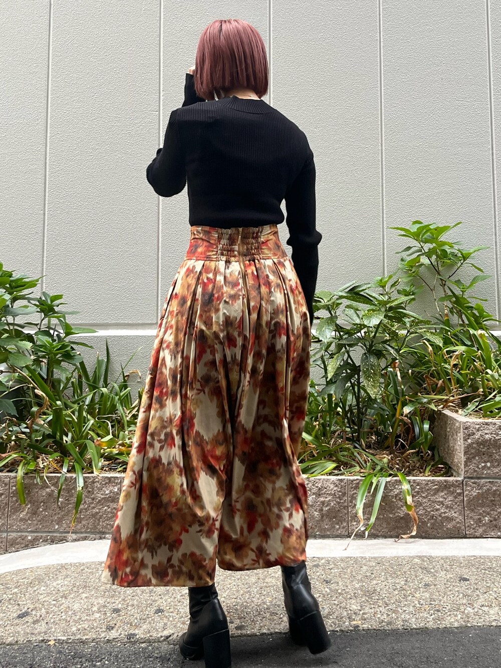 オレンジ系のスカート、ブラック系のニット/セーター、ベージュ系のムートンコートを着用したレディースの秋コーディネートの5枚目の写真