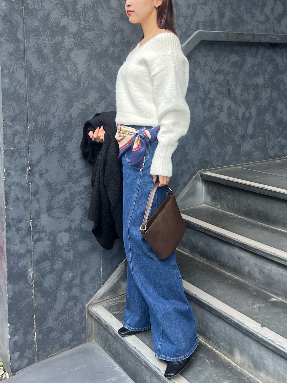 ホワイト系のニット/セーター、ブルー系のデニムパンツ、ブラウン系のハンドバッグを着用したレディースの冬コーディネートの2枚目の写真