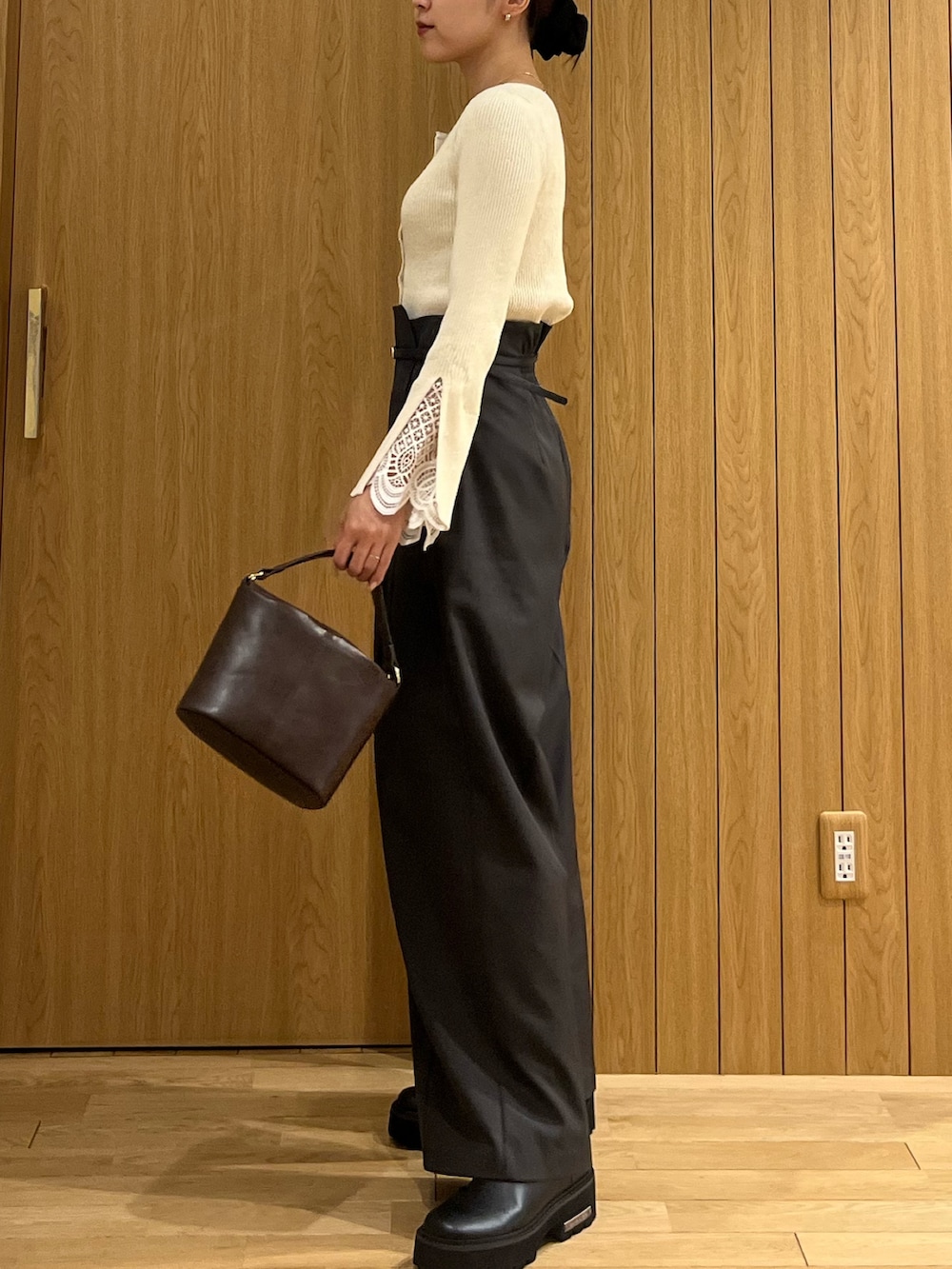 グレー系のその他パンツ、ホワイト系のニット/セーター、ブラウン系のハンドバッグを着用したレディースの冬コーディネートの2枚目の写真