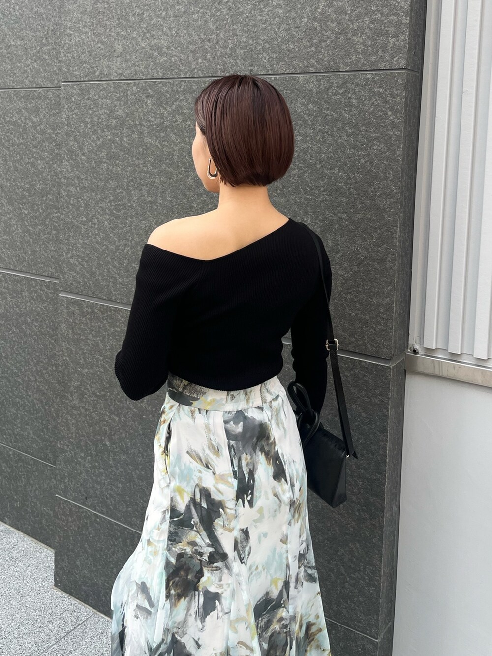 ブルー系のスカート、シルバー系のパンプス、ブラック系のハンドバッグを着用したレディースの春コーディネートの6枚目の写真