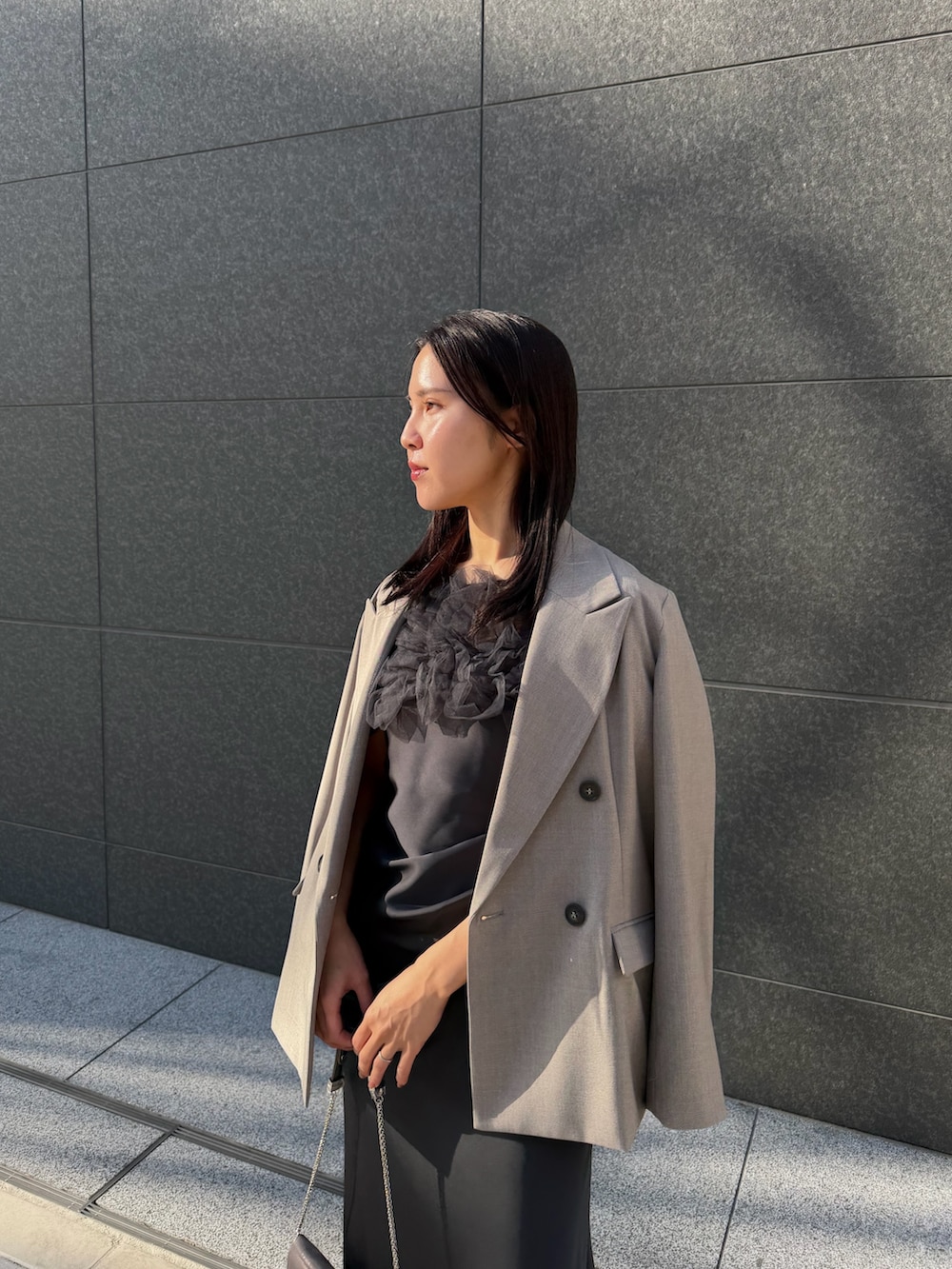 シルバー系のクラッチバッグ、シルバー系のパンプス、グレー系のドレスを着用したレディースの冬コーディネートの3枚目の写真