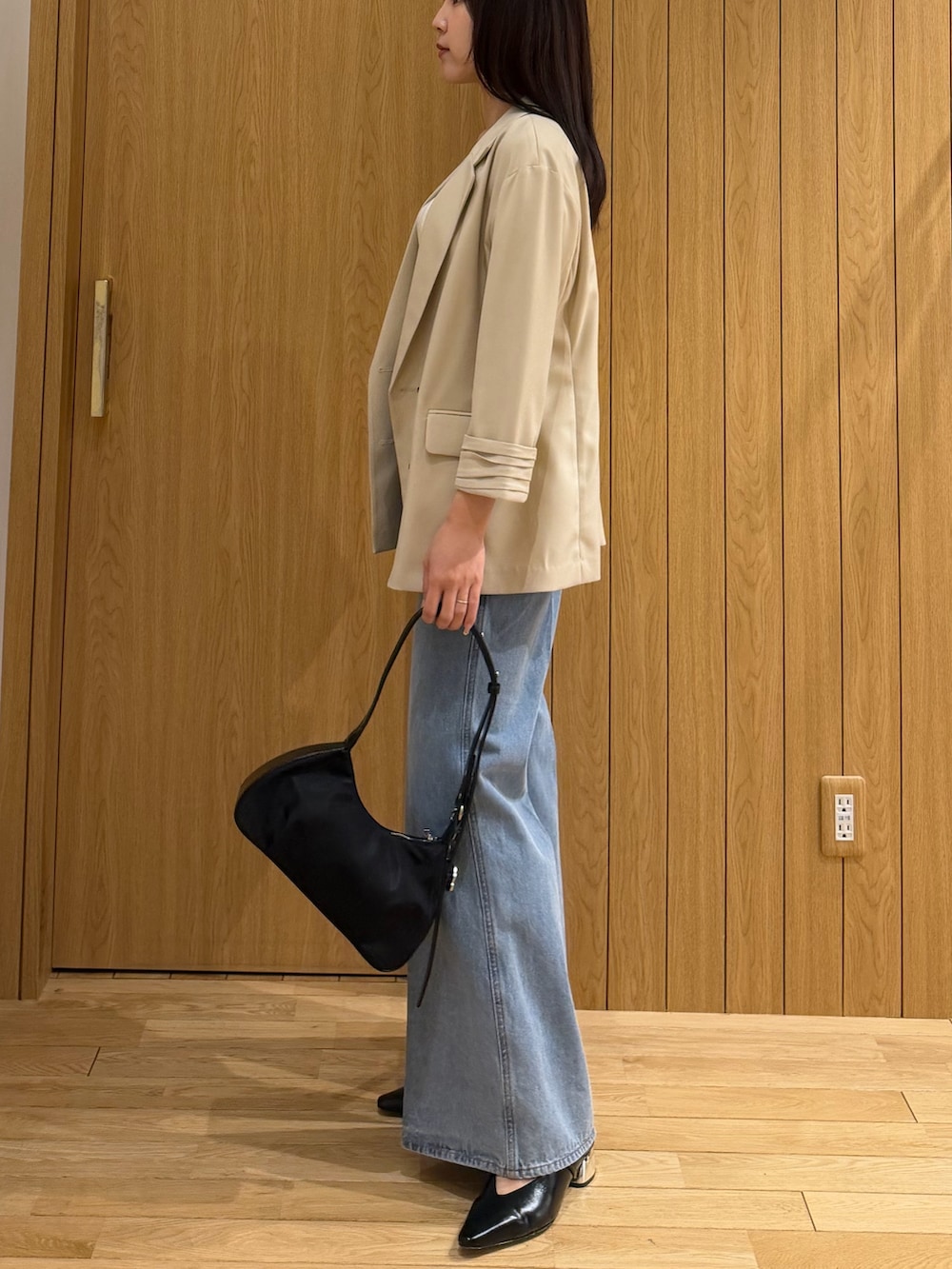 ブルー系のデニムパンツ、ホワイト系のタンクトップ、ベージュ系のテーラードジャケットを着用したレディースの春コーディネートの2枚目の写真