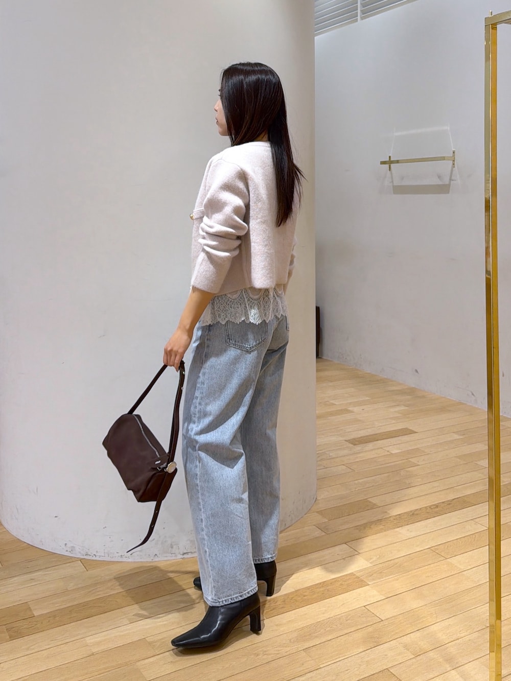 ベージュ系のノーカラージャケット、ベージュ系のキャミソール、ブルー系のデニムパンツを着用したレディースの秋コーディネートの2枚目の写真