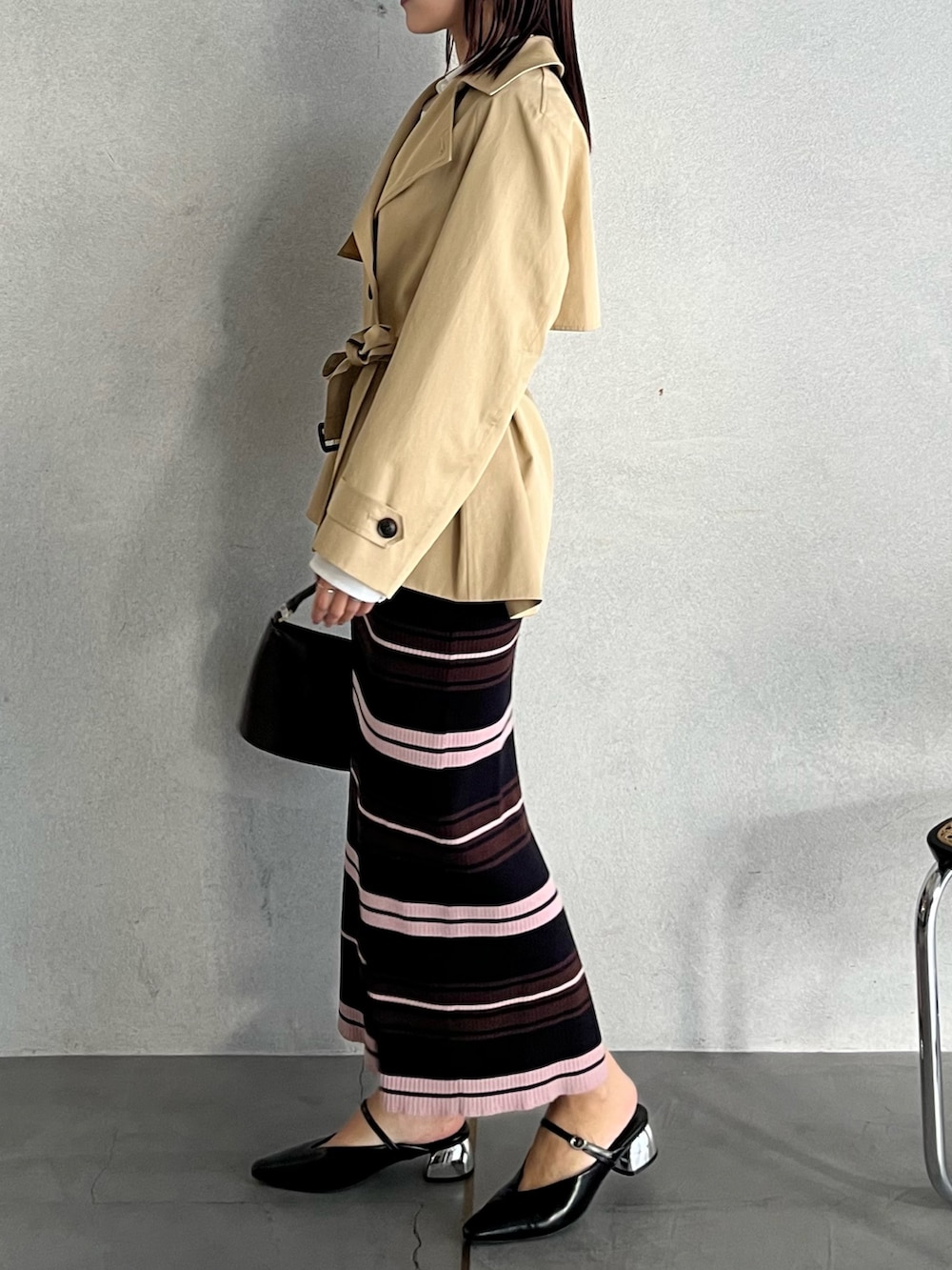 ブラウン系のハンドバッグ、ブラウン系のワンピース、ベージュ系のトレンチコートを着用したレディースの冬コーディネートの2枚目の写真