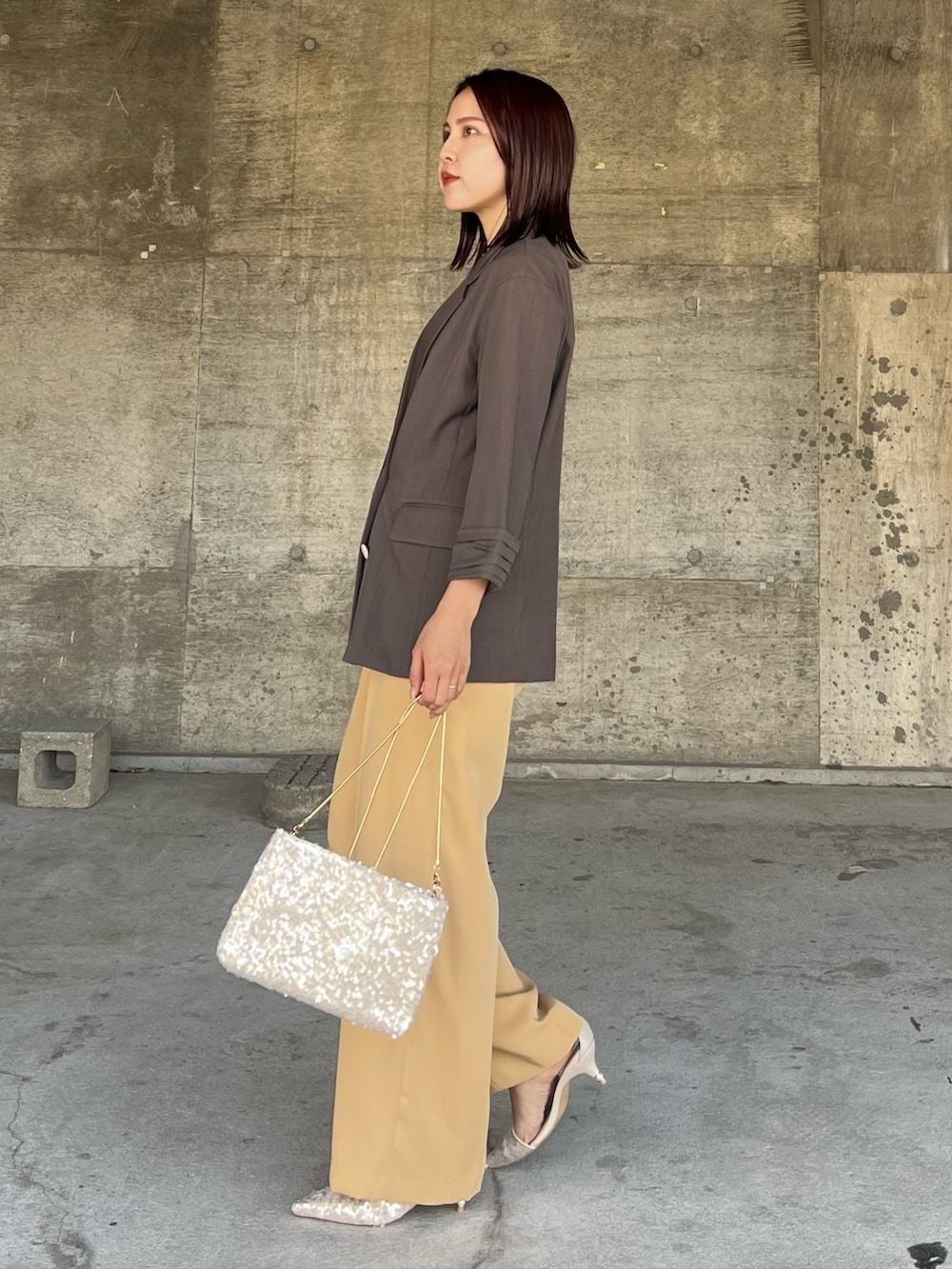 イエロー系のパンツドレス、ベージュ系のパンプス、ベージュ系のショルダーバッグを着用したレディースの春コーディネートの2枚目の写真