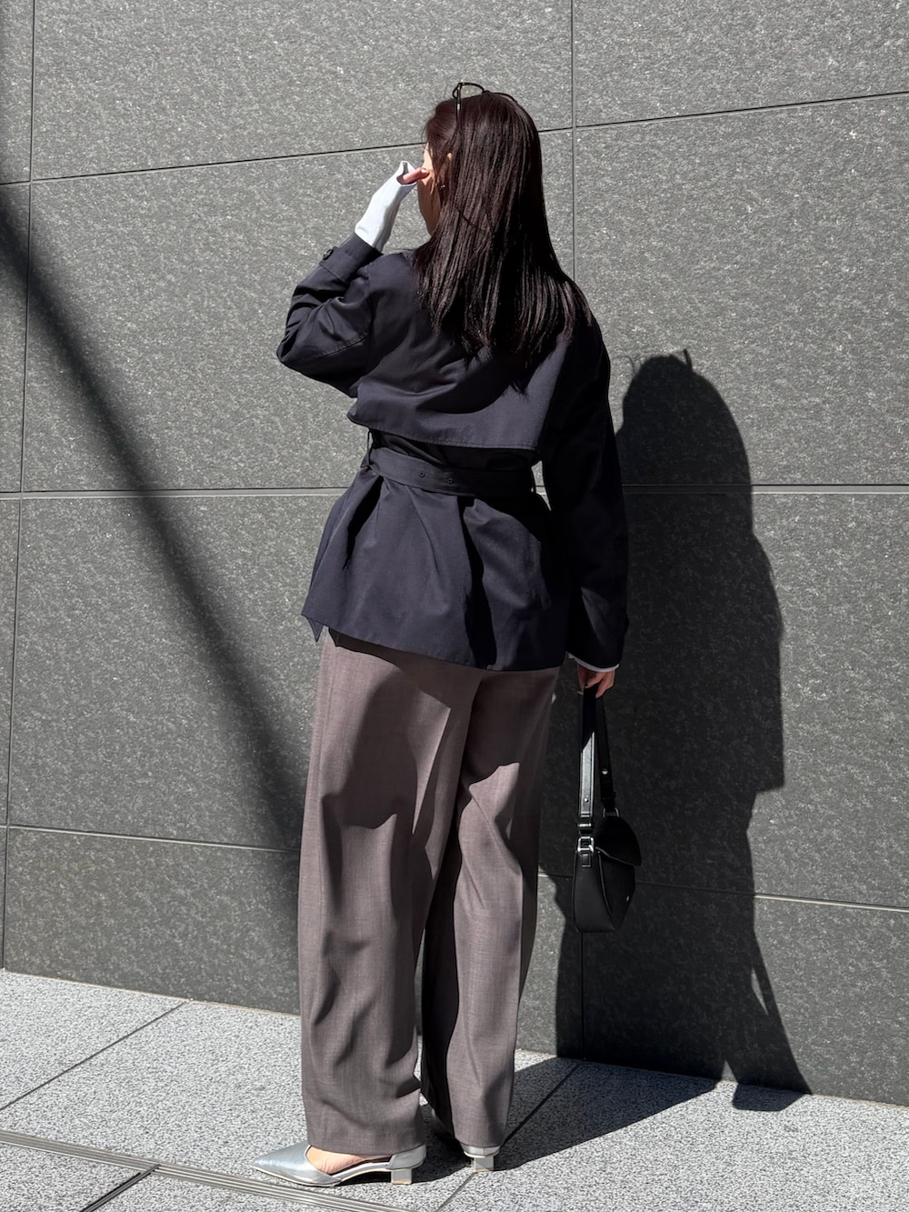 ブルー系のトレンチコート、グレー系のその他パンツ、ブラック系のハンドバッグを着用したレディースの冬コーディネートの3枚目の写真