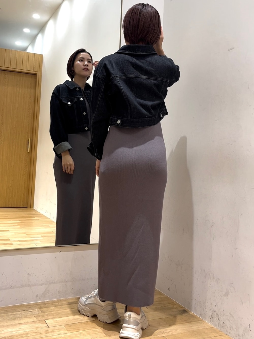 ブラック系のデニムジャケット、グレー系のワンピースを着用したレディースの冬コーディネートの3枚目の写真