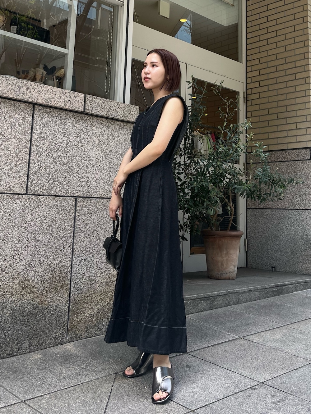 ブラック系のワンピース、その他のサンダル、ブラック系のハンドバッグを着用したレディースの春コーディネートの2枚目の写真