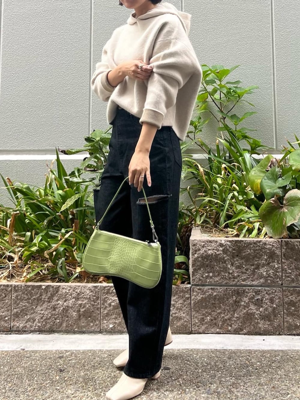 ホワイト系のブーツ、ブラック系のデニムパンツ、グリーン系のハンドバッグを着用したレディースの秋コーディネートの2枚目の写真