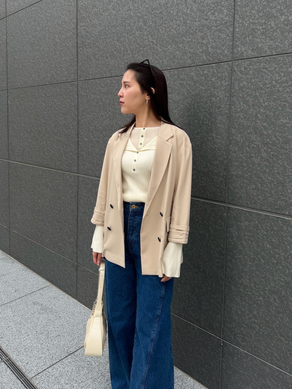 ベージュ系のテーラードジャケット、ホワイト系のニット/セーター、ブルー系のデニムパンツを着用したレディースの春コーディネートの4枚目の写真