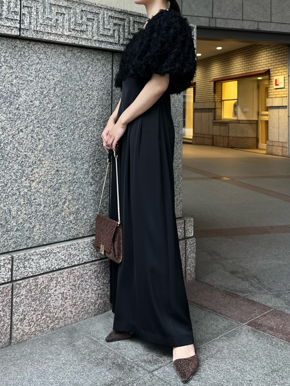 その他のパンプス、ブラック系のパンツドレス、その他のクラッチバッグを着用したレディースの冬コーディネートの3枚目の写真