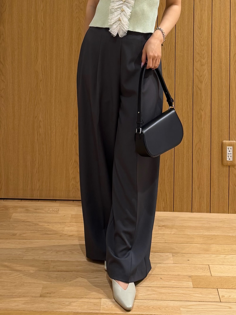 グレー系のその他パンツ、ブラック系のハンドバッグ、グリーン系のニット/セーターを着用したレディースの夏コーディネートの7枚目の写真