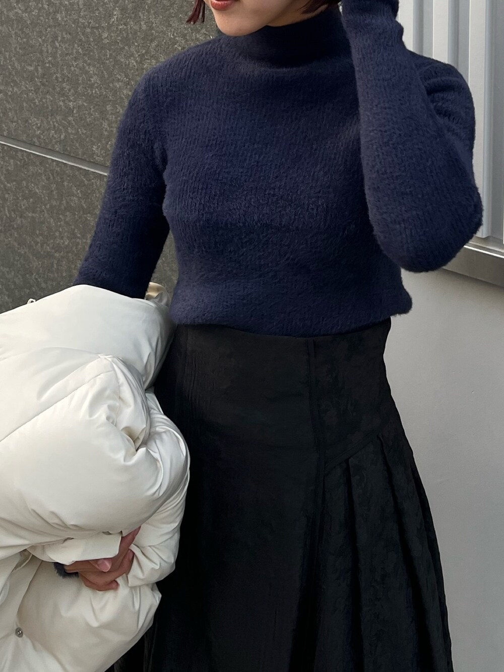 ホワイト系のダウンジャケット/コート、ブルー系のニット/セーター、ブラック系のスカートを着用したレディースの冬コーディネートの6枚目の写真