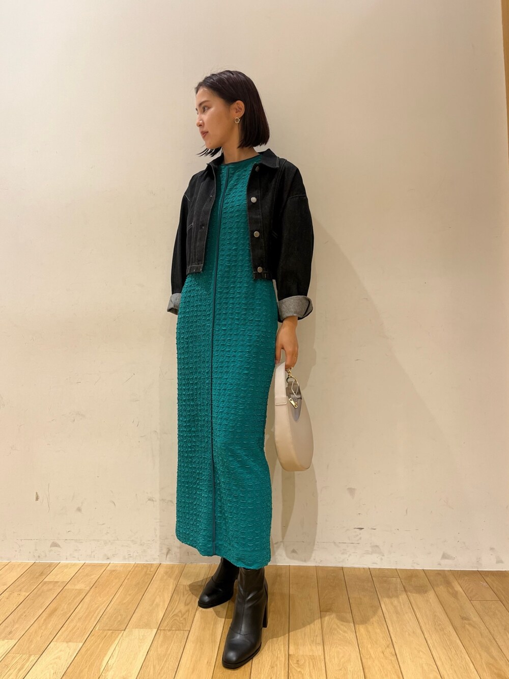 グリーン系のワンピース、ホワイト系のハンドバッグ、ブラック系のデニムジャケットを着用したレディースの夏コーディネートの3枚目の写真