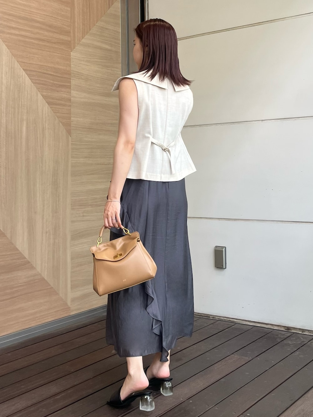 ホワイト系のベスト、グレー系のワンピース、ブラウン系のハンドバッグを着用したレディースの夏コーディネートの3枚目の写真
