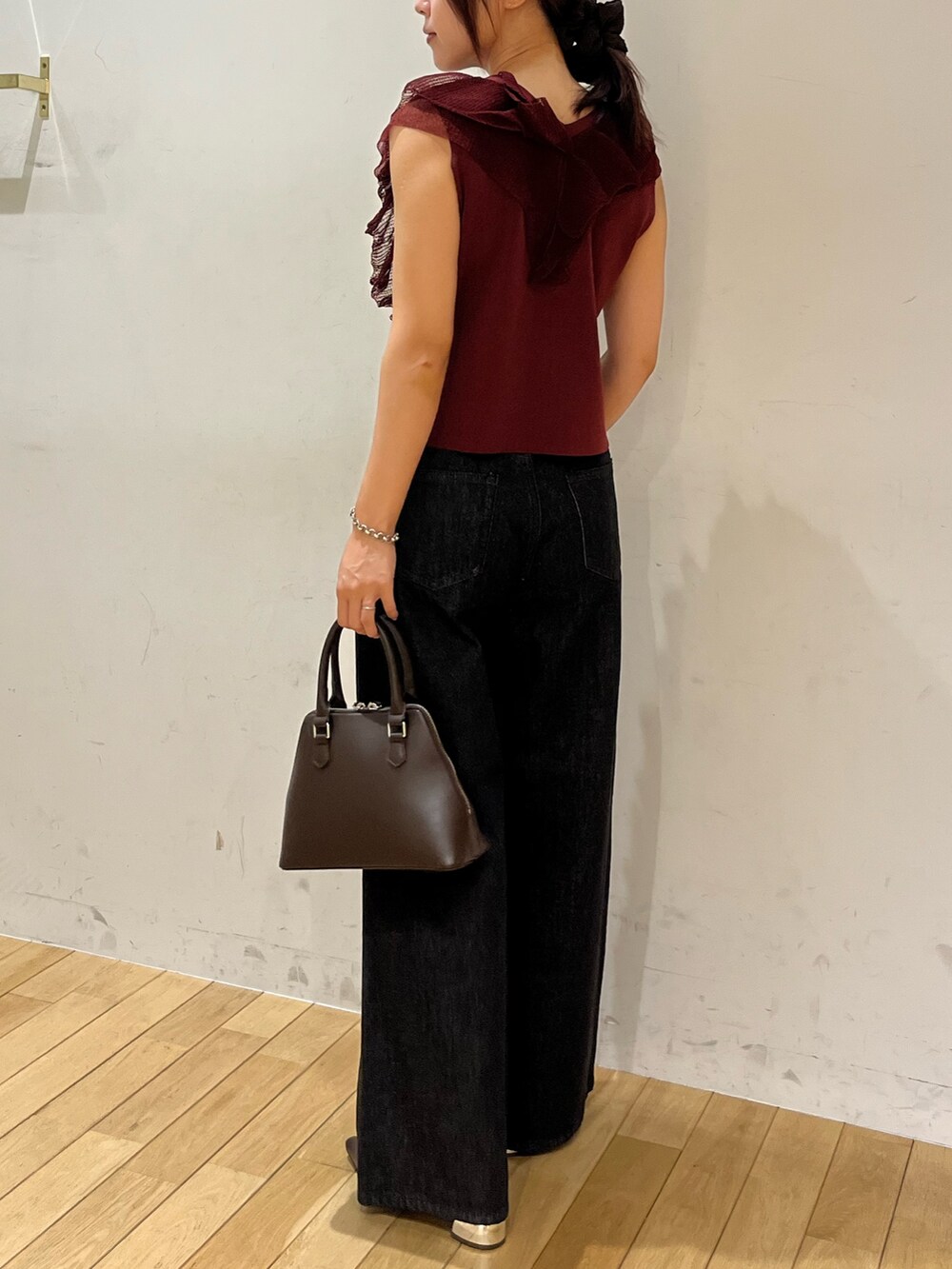 ブラック系のデニムパンツ、ブラウン系のパンプス、ブラウン系のボストンバッグを着用したレディースの夏コーディネートの3枚目の写真