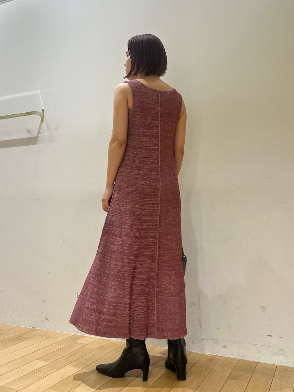 パープル系のワンピース、ブラック系のショルダーバッグ、ブラック系のブーツを着用したレディースの夏コーディネートの3枚目の写真