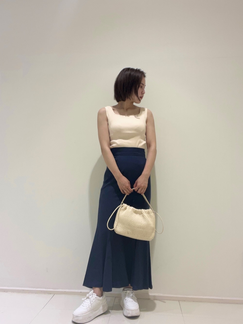 ホワイト系のニット/セーター、ブルー系のスカート、ブルー系のシャツ/ブラウスを着用したレディースの春コーディネートの6枚目の写真