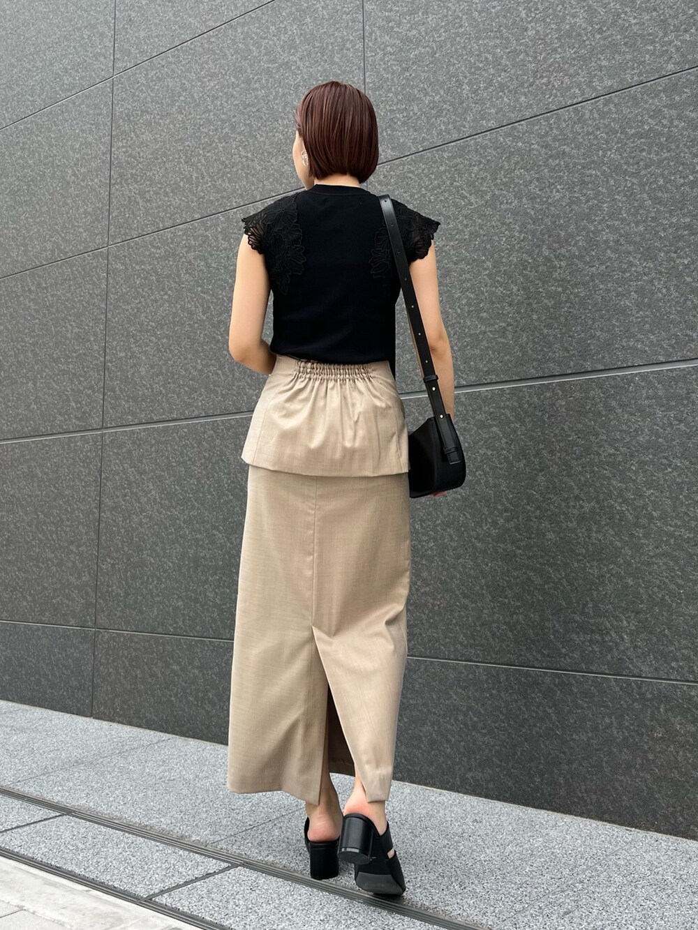 ブラック系のサンダル、ブラック系のニット/セーター、ベージュ系のスカートを着用したレディースの春コーディネートの4枚目の写真