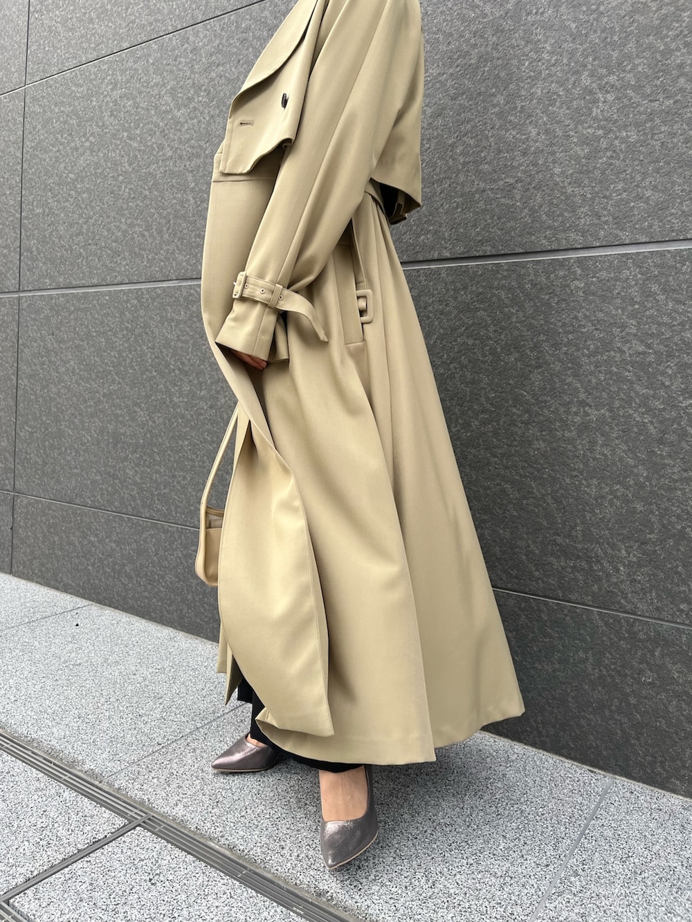 グリーン系のトレンチコート、シルバー系のパンプス、ブラック系のパンツドレスを着用したレディースの春コーディネートの7枚目の写真