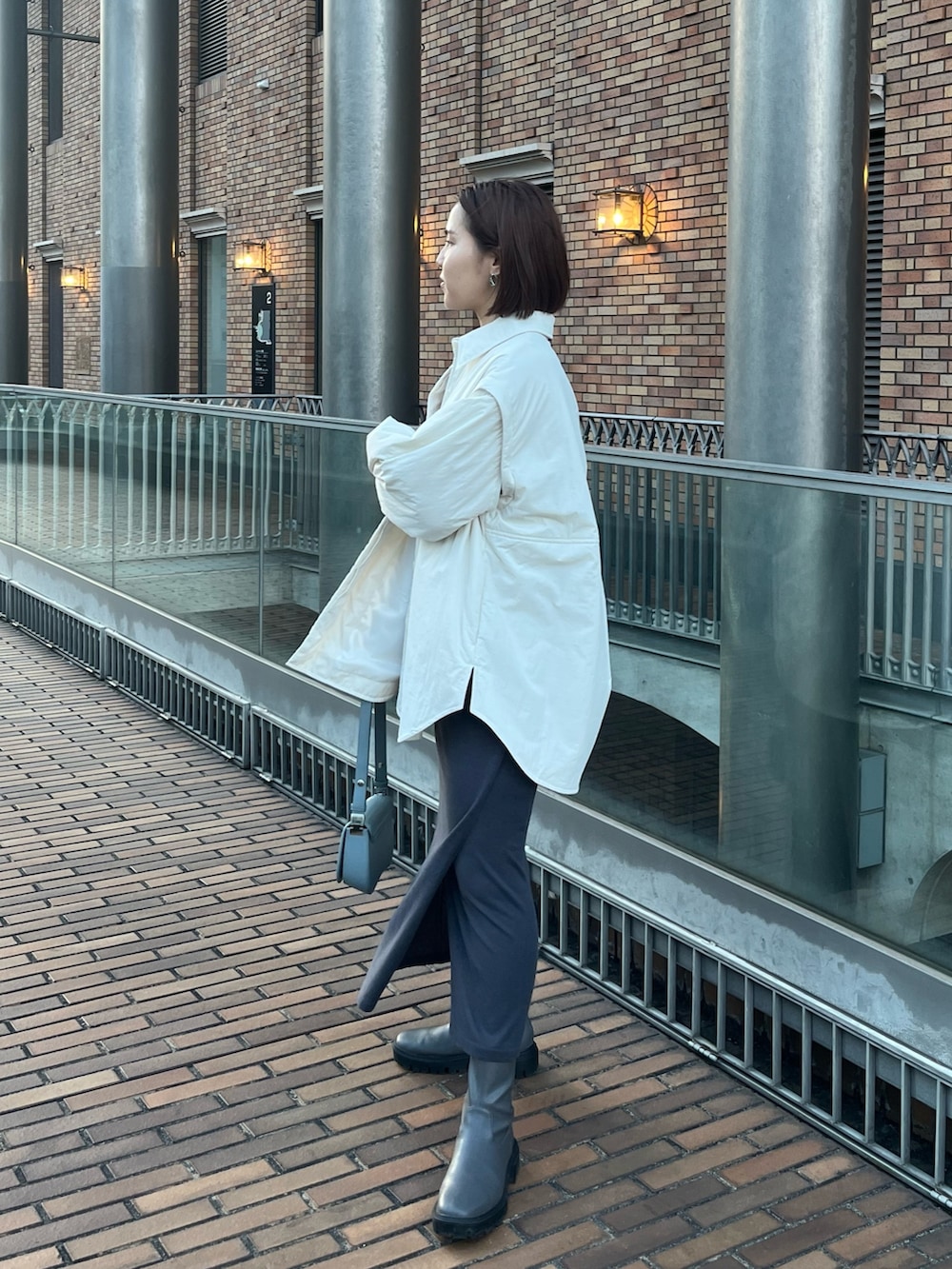 ブルー系のショルダーバッグ、グレー系のスカート、ホワイト系のブルゾンを着用したレディースの冬コーディネートの2枚目の写真