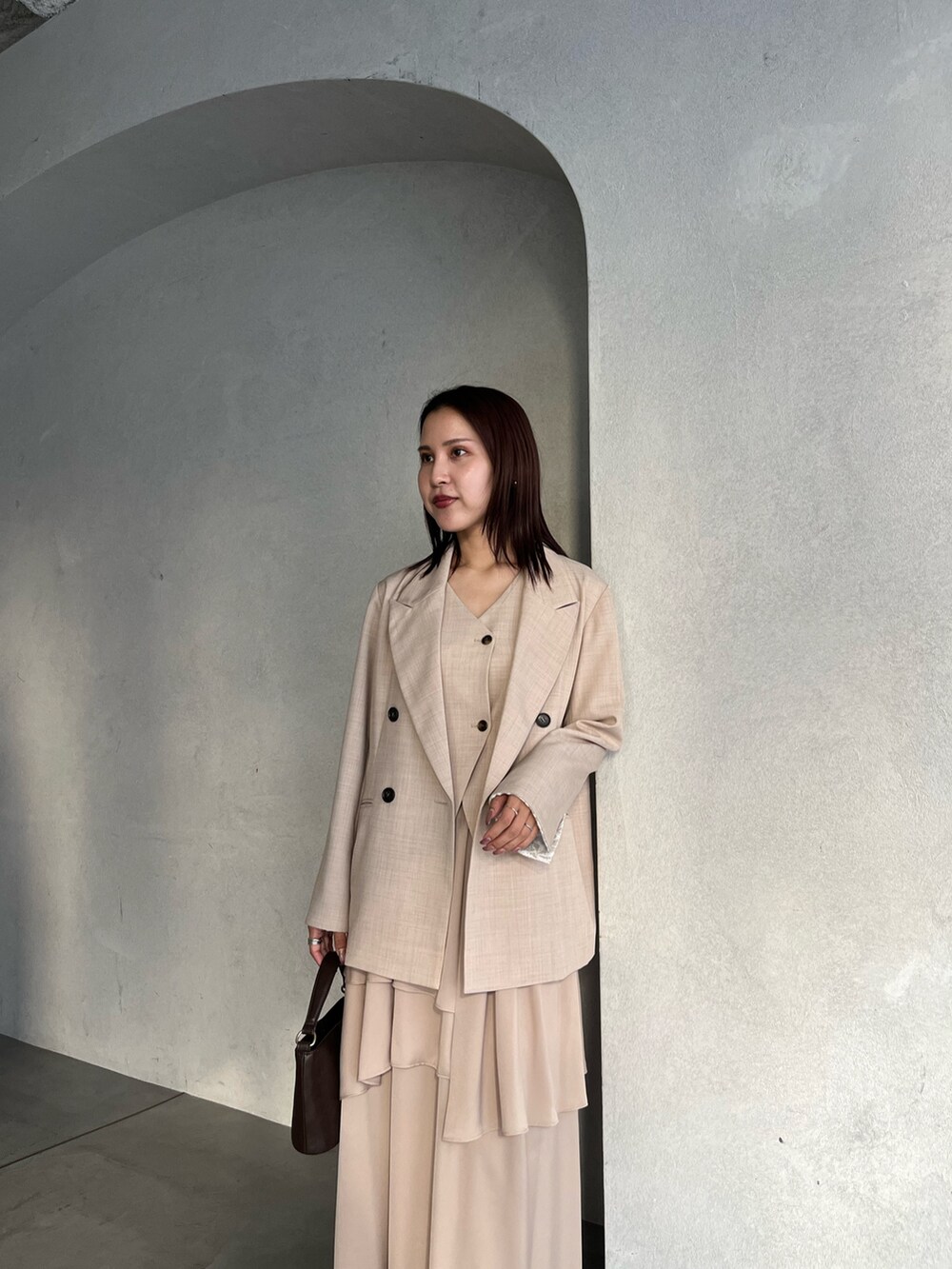 ベージュ系のテーラードジャケット、ベージュ系のワンピース、ブラウン系のハンドバッグを着用したレディースの冬コーディネートの5枚目の写真