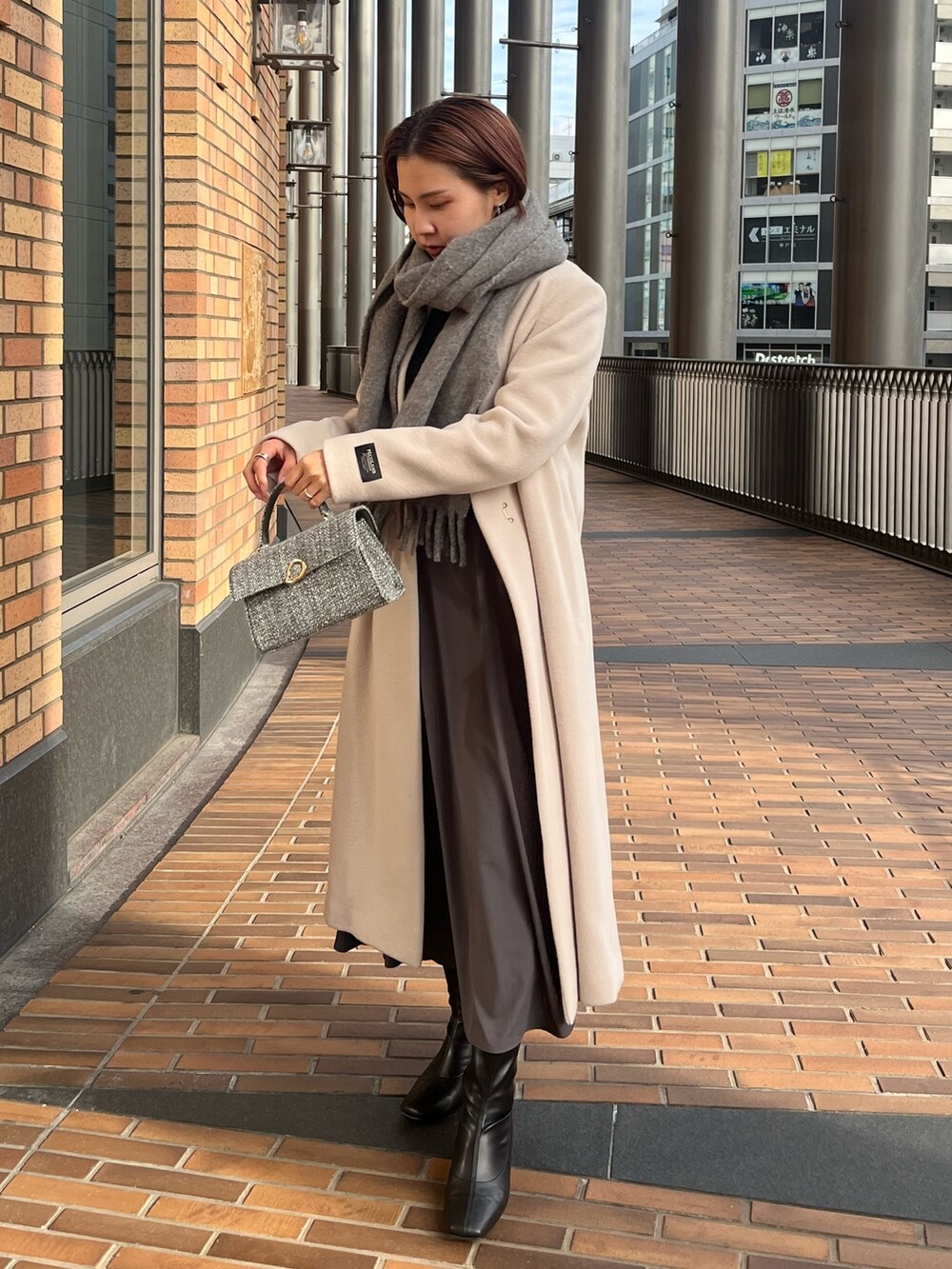 ホワイト系のノーカラーコート、ブラック系のワンピース、グレー系のショルダーバッグを着用したレディースの冬コーディネートの2枚目の写真