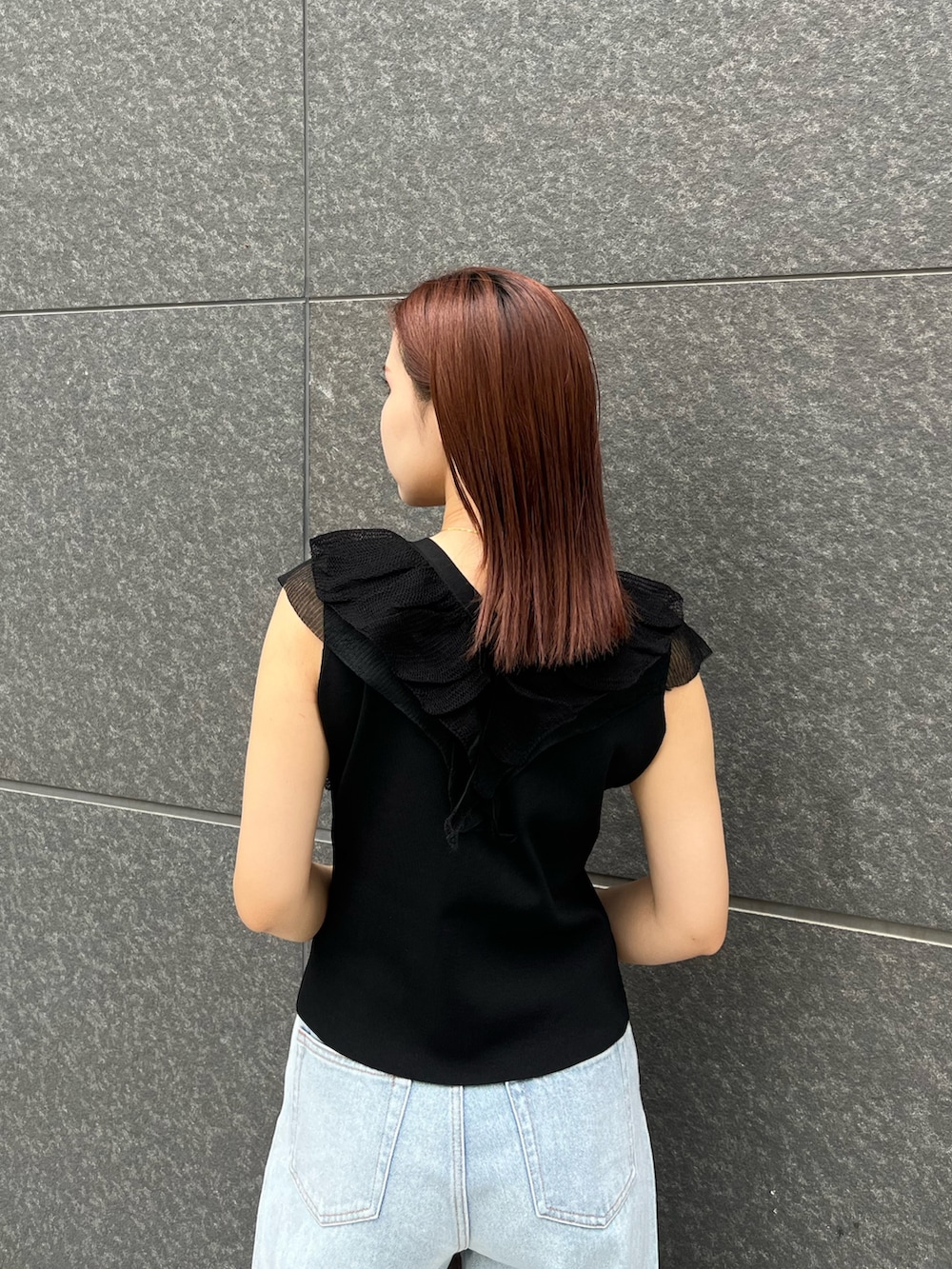 ブラック系のニット/セーター、ブルー系のデニムパンツ、ベージュ系のボストンバッグを着用したレディースの夏コーディネートの6枚目の写真