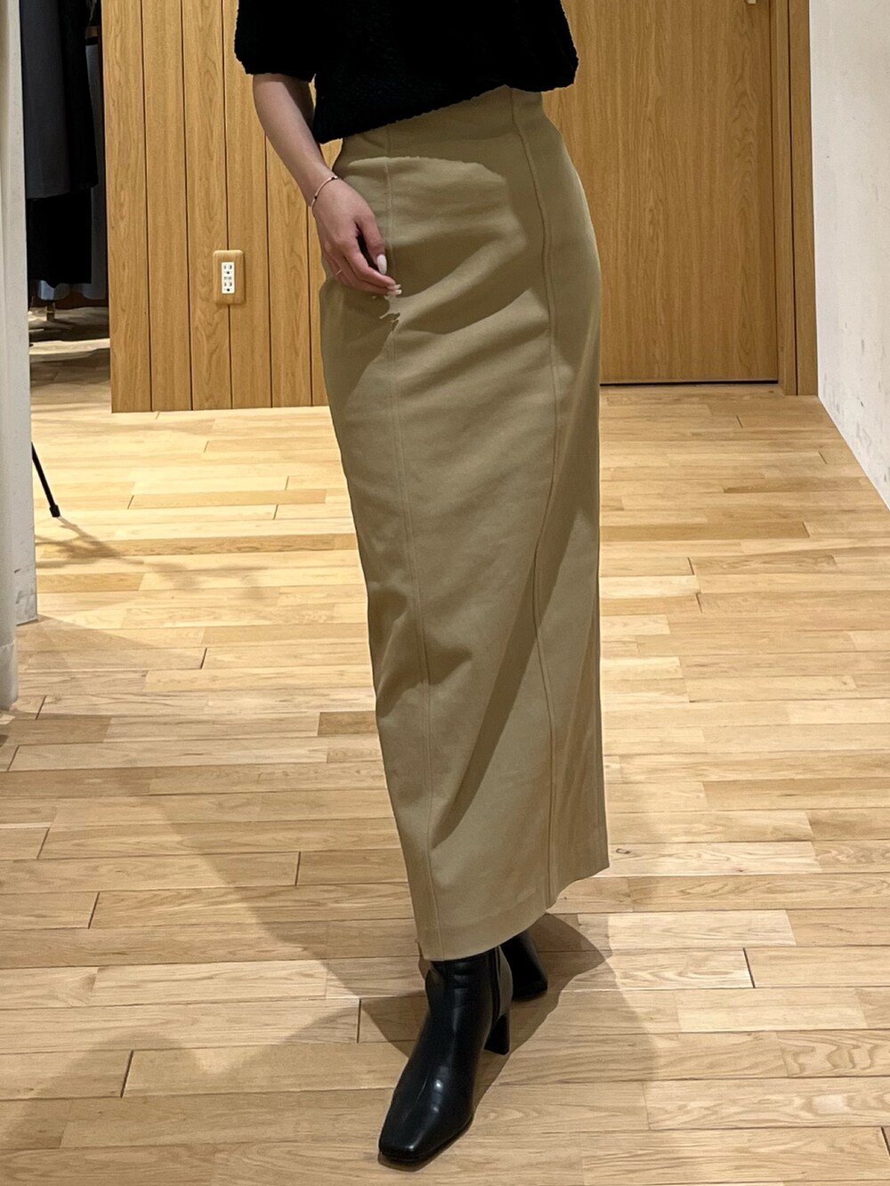 ブラック系のブーツ、ベージュ系のスカート、ブラウン系のボストンバッグを着用したレディースの秋コーディネートの4枚目の写真