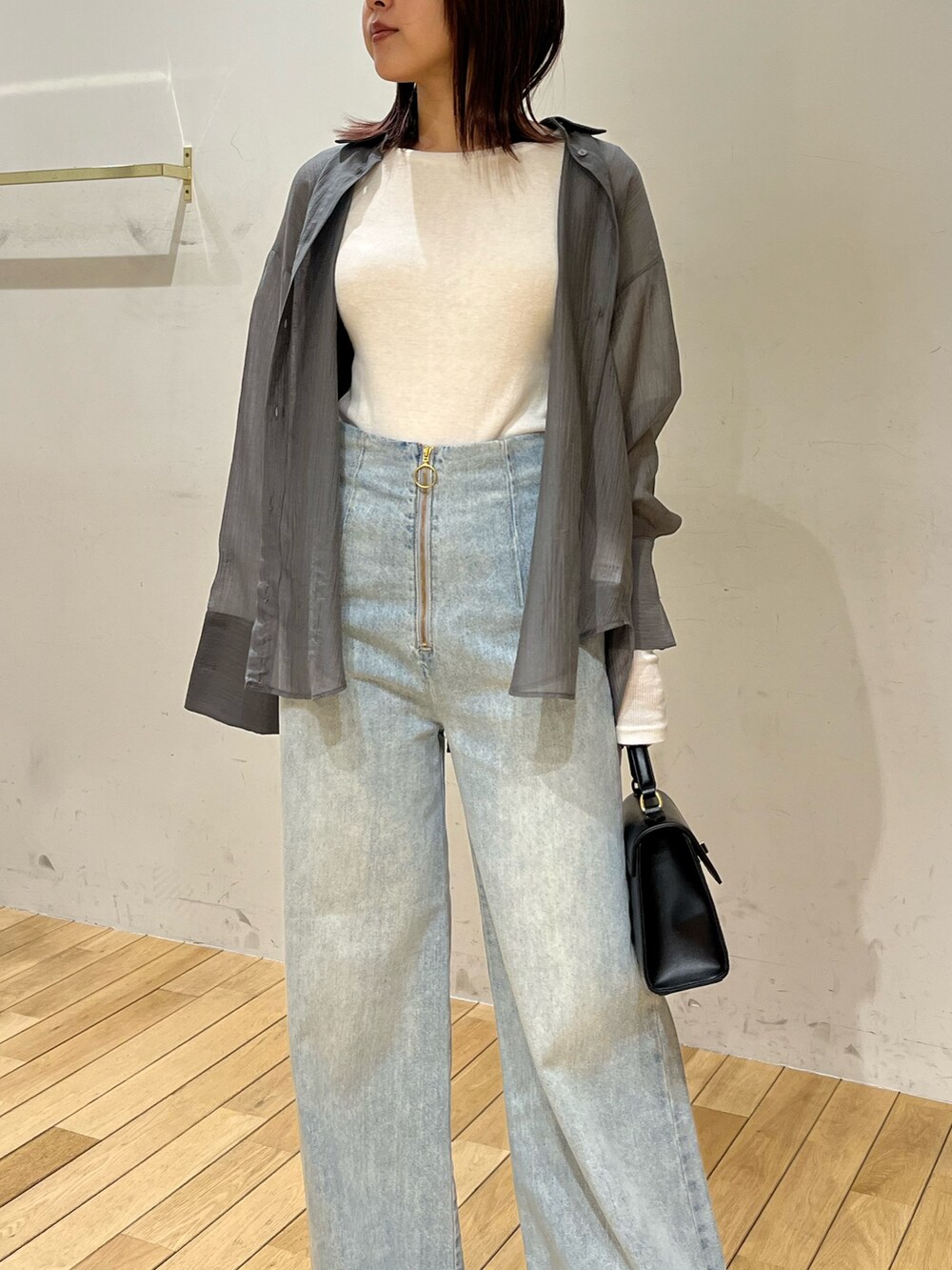 ホワイト系のサンダル、ブラック系のハンドバッグ、ブルー系のデニムパンツを着用したレディースの春コーディネートの5枚目の写真