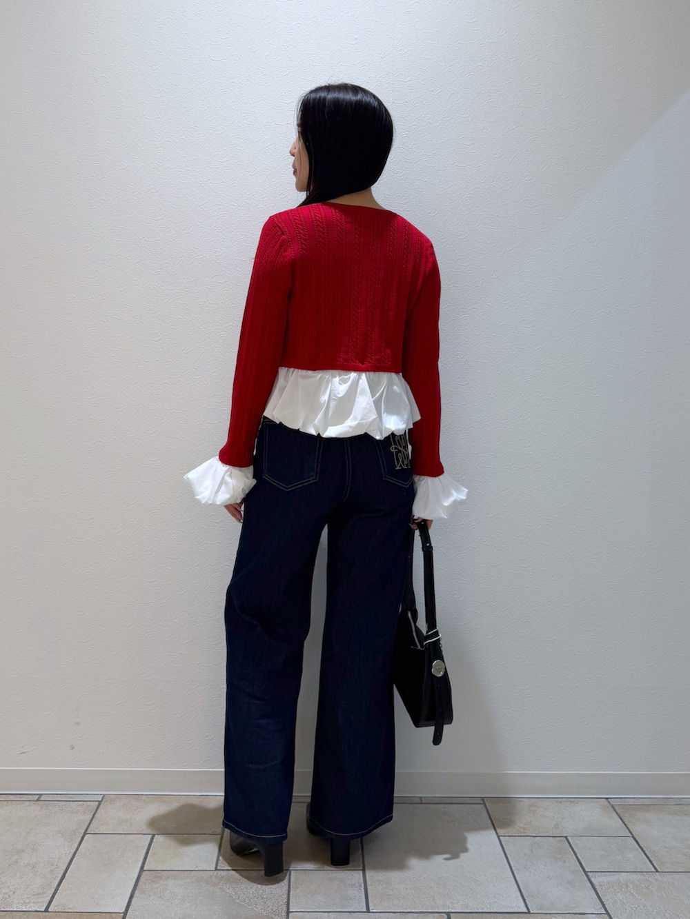 レッド系のカーディガン/ボレロ、ブルー系のデニムパンツ、ブラック系のブーツを着用したレディースの秋コーディネートの3枚目の写真
